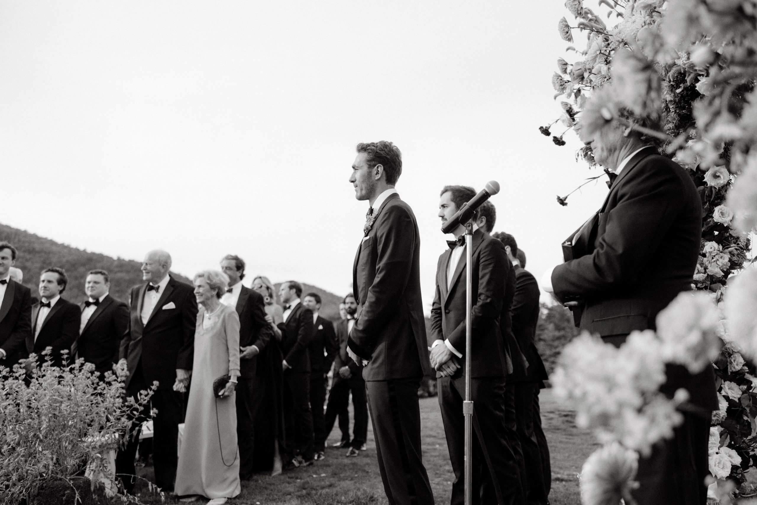 Black and white photo of the groom watching the bride walk down the aisle. Image by Jenny Fu Studio