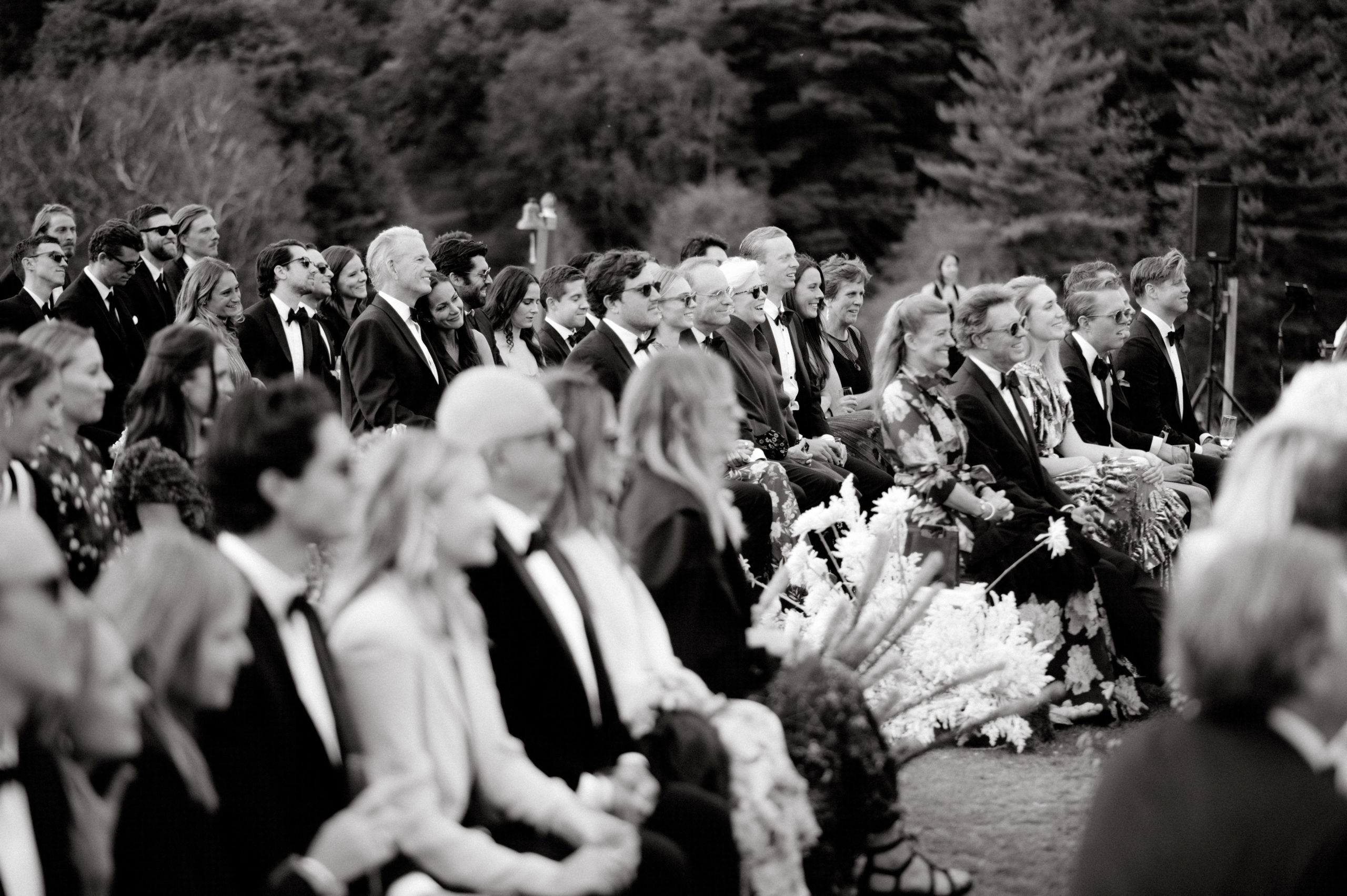 Black and white photo of the guests happily watching the wedding ceremony. Candid wedding photography image by Jenny Fu Studio