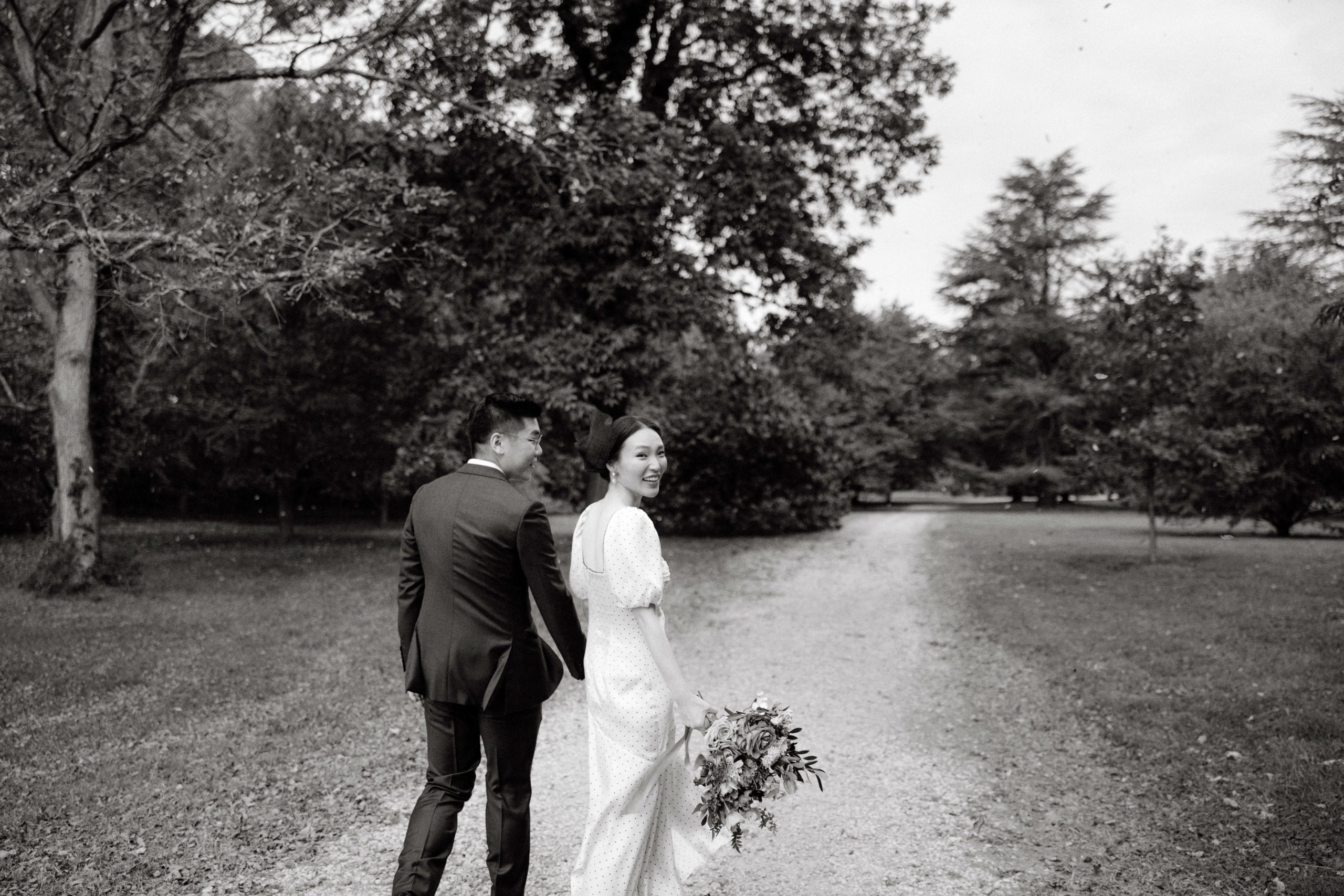 Candid black and white photo of the engaged couple walking in the grounds of Planting Fields Arboretum, NY. Engagement session photo by Jenny Fu Studio