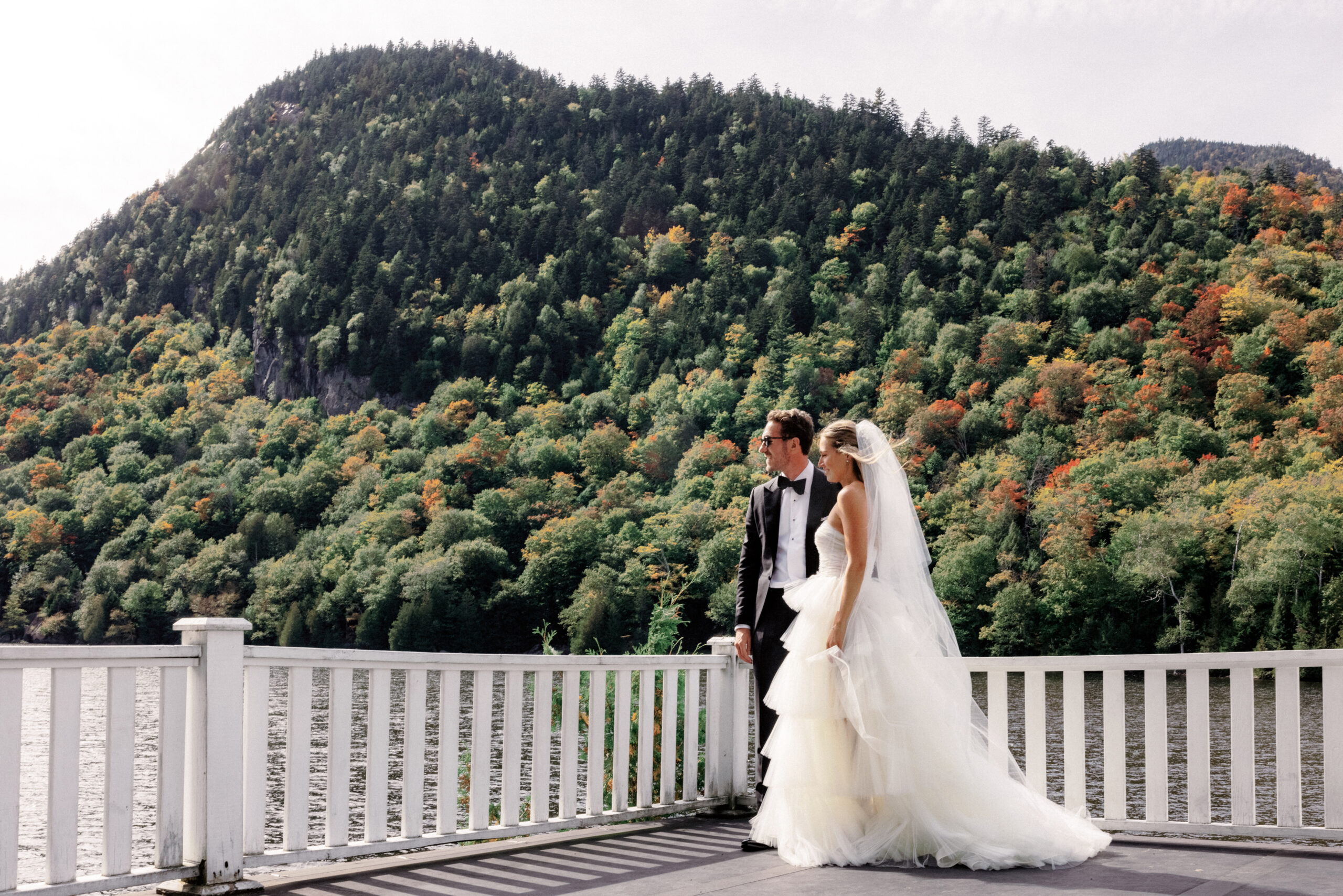 The bride and groom are looking over the lake at The Ausable Club New York. Upstate New York luxury wedding image by Jenny Fu Studio.