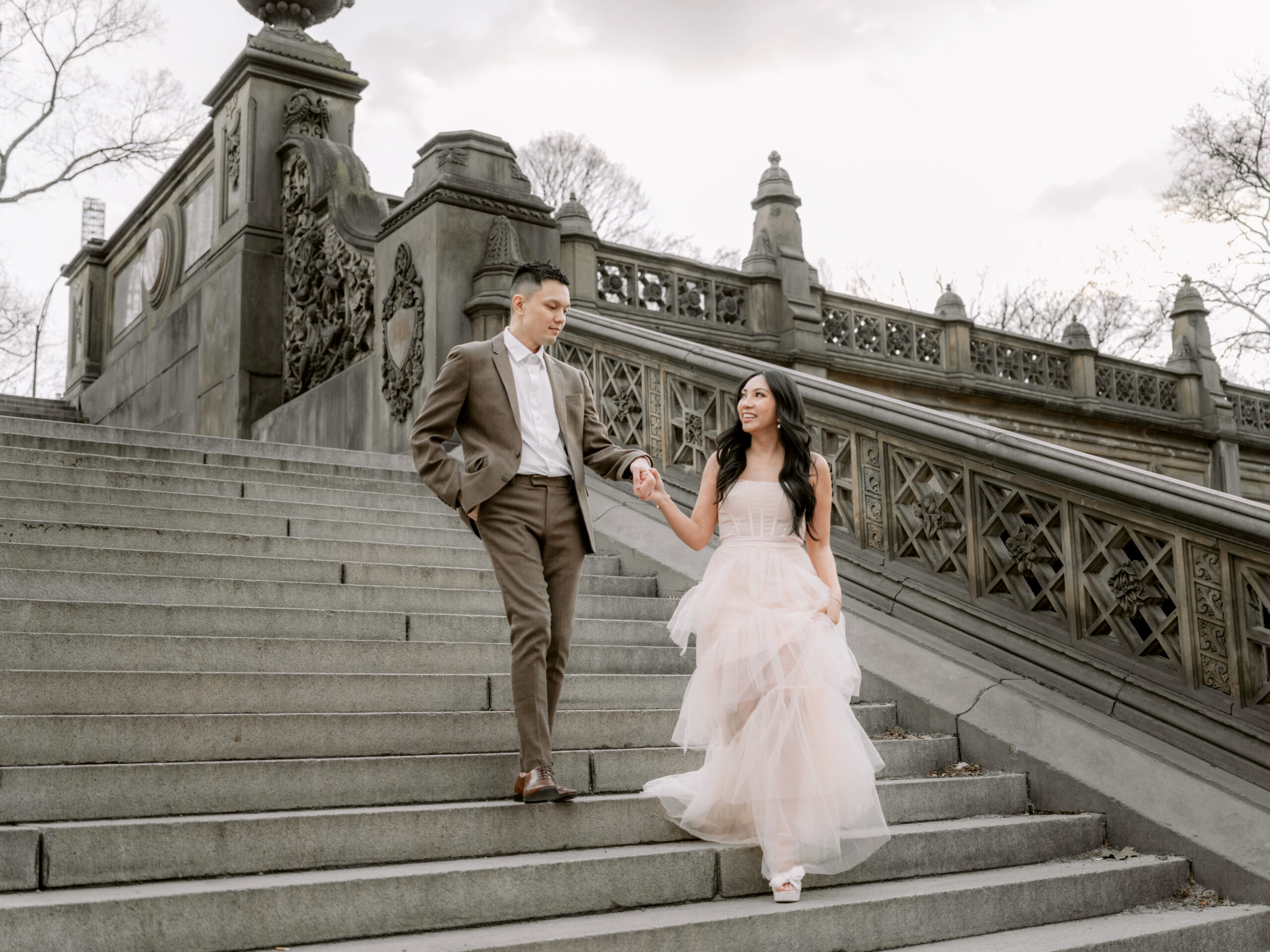 The engaged couple is walking down the staircase in a park. Image by Jenny Fu Studio