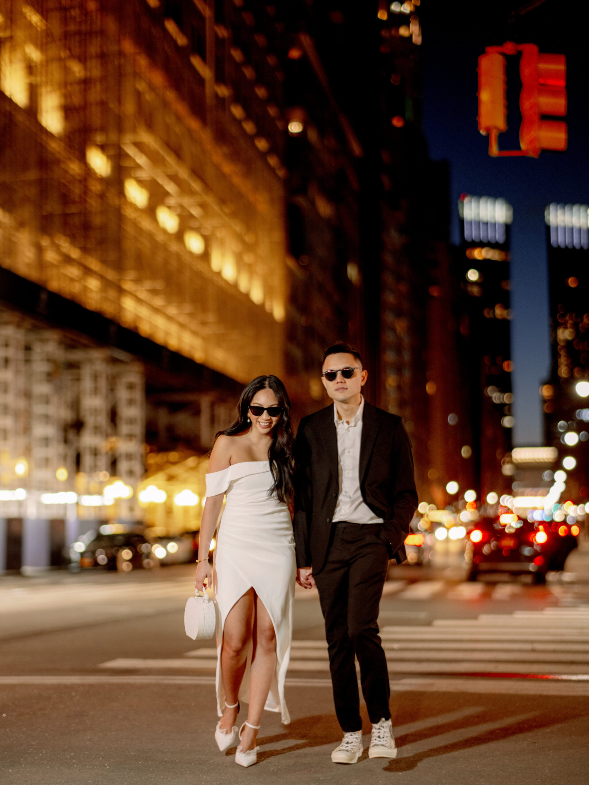 Night time photo of the engaged couple wearing sunglasses, walking the streets of New York. Image by Jenny Fu Studio
