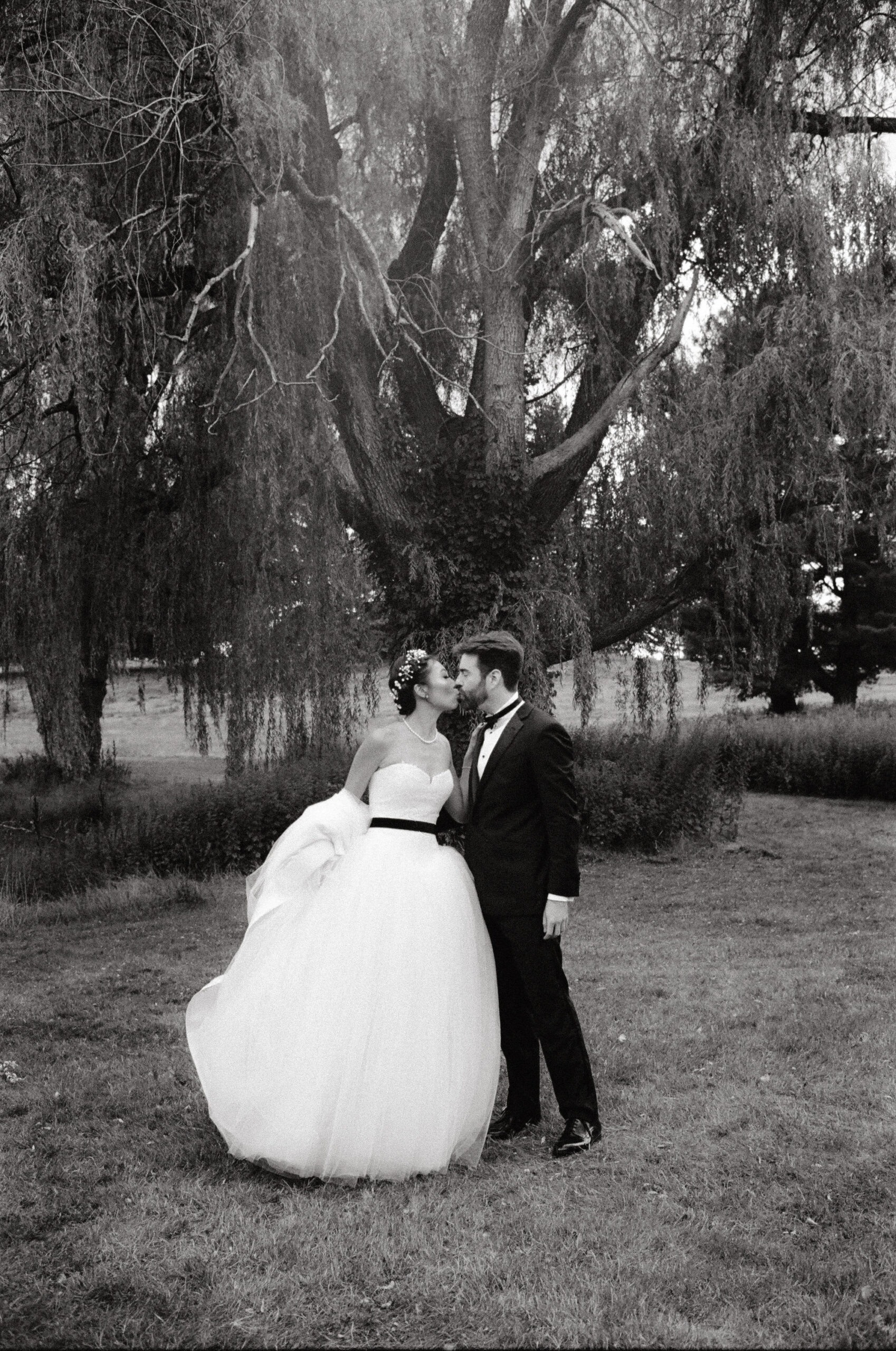 Black and white editorial photo of the bride and groom kissing. Film photography image by Jenny Fu Studio