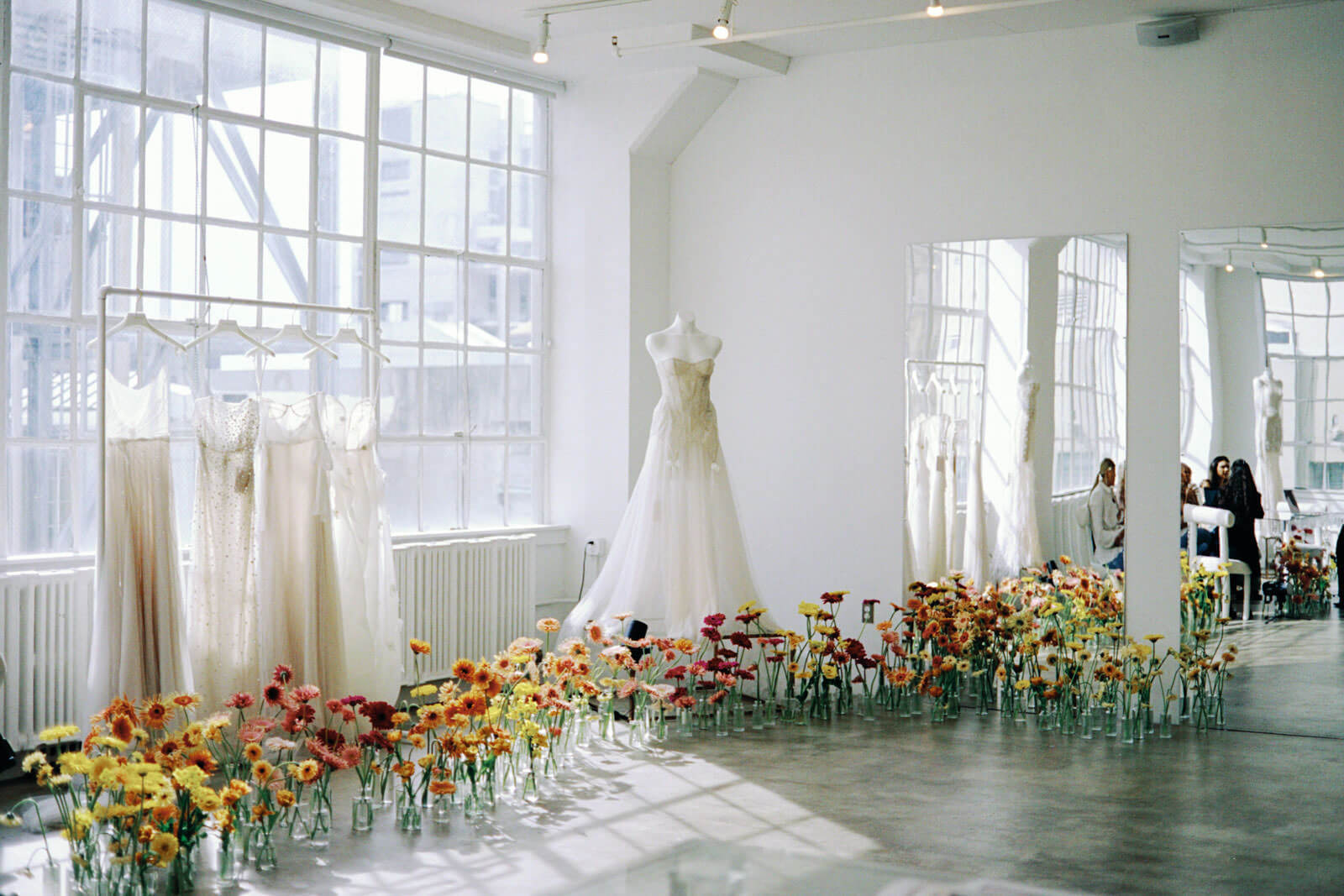 Bridal gowns on display in a room filled with flowers in the New York Bridal Fashion week. Image by Jenny Fu