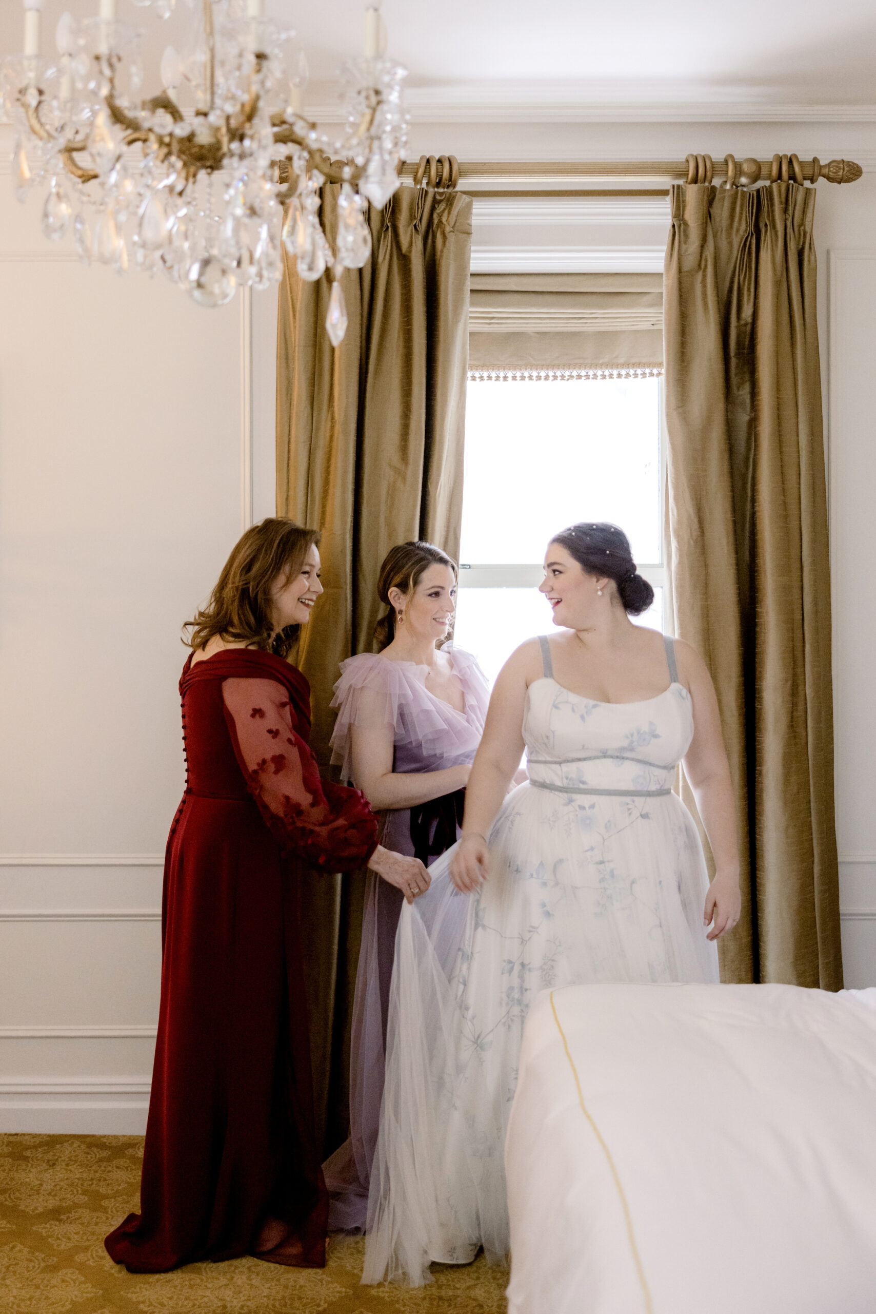 The bride's mom and her sister are fixing her wedding dress. Capturing emotions image by Jenny Fu Studio 