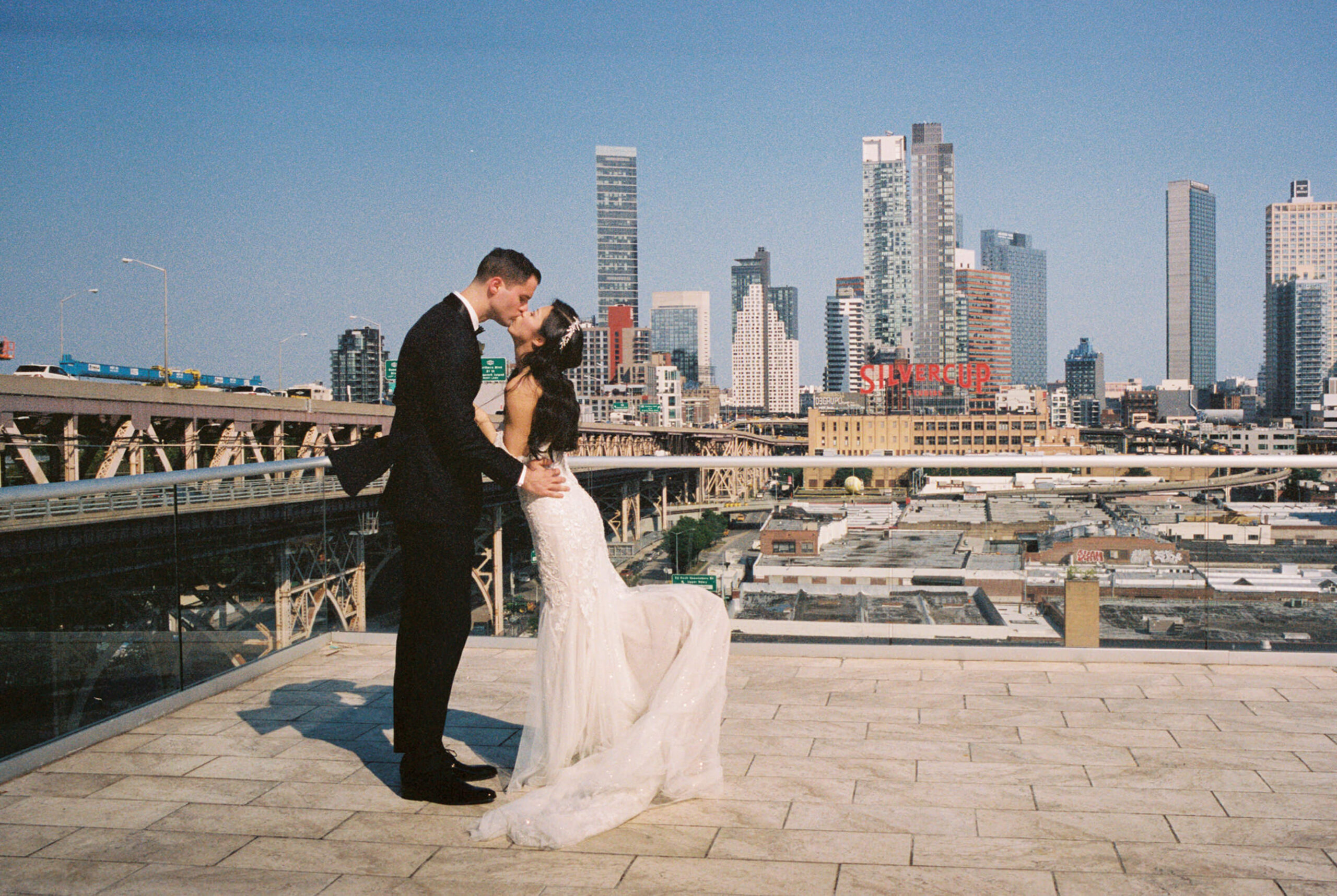 Editorial photo of the bride and groom in NYC with skyscrapers in the background. Film wedding photography image by Jenny Fu Studio
