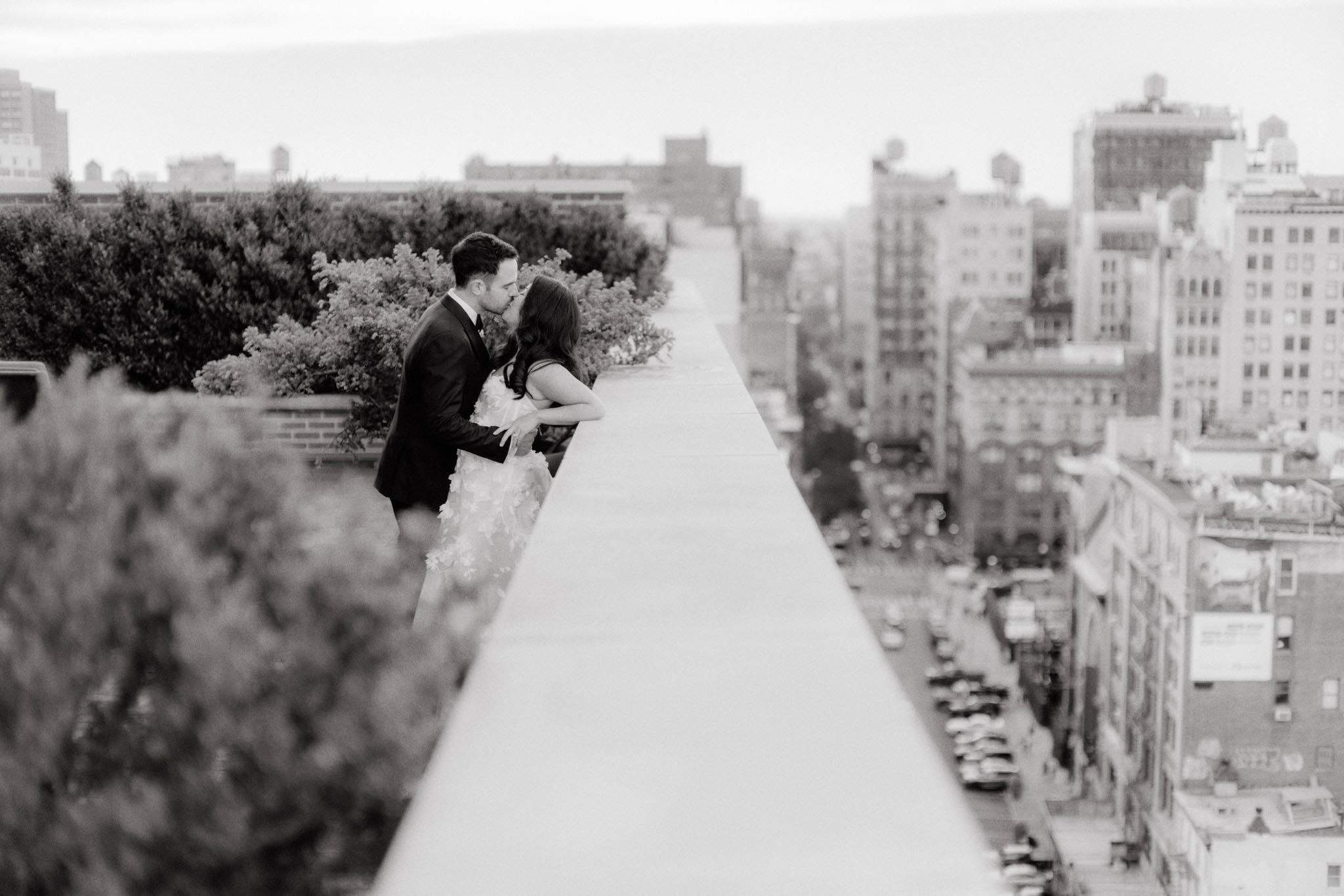 Black and white photo of the bride and groom kissing in the outdoor terrace at The Bowery Hotel. Image by Jenny Fu Studio