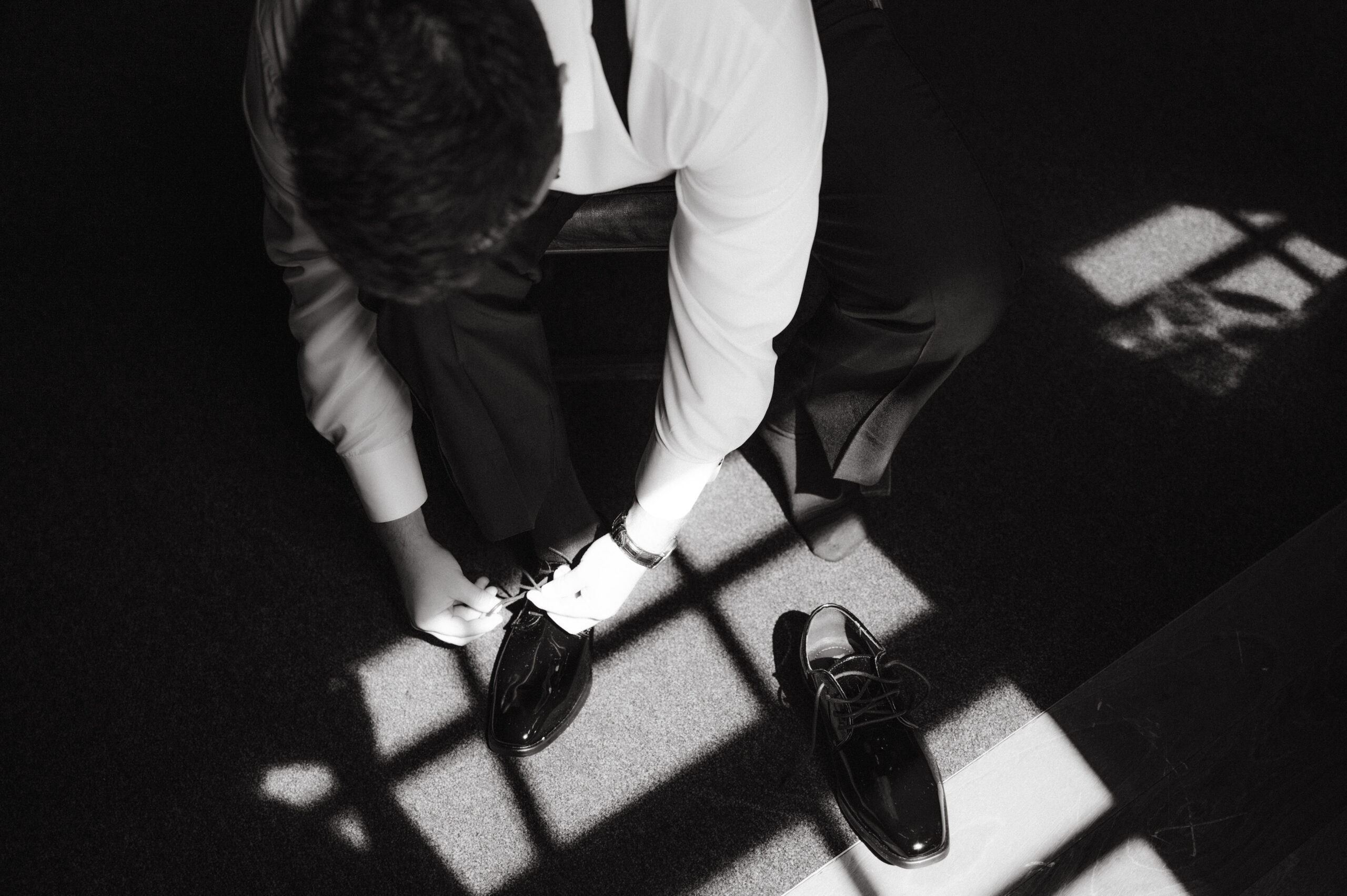 Editorial photo of the groom wearing his shoes. Timeless wedding photography Image by Jenny Fu Studio