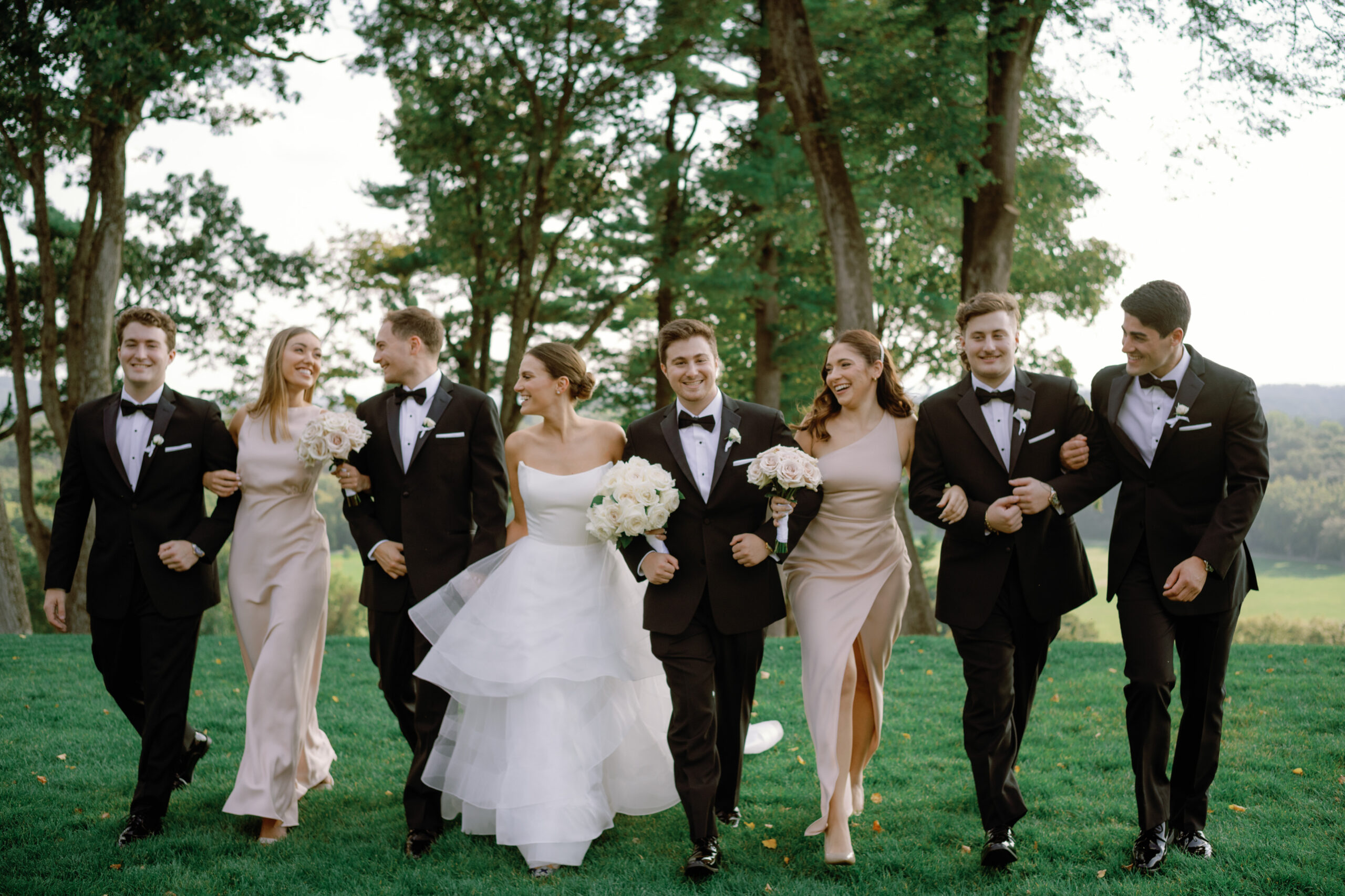 Editorial image of the bride and groom walking outdoors with their bridesmaids and groomsmen. Image by Jenny Fu Studio