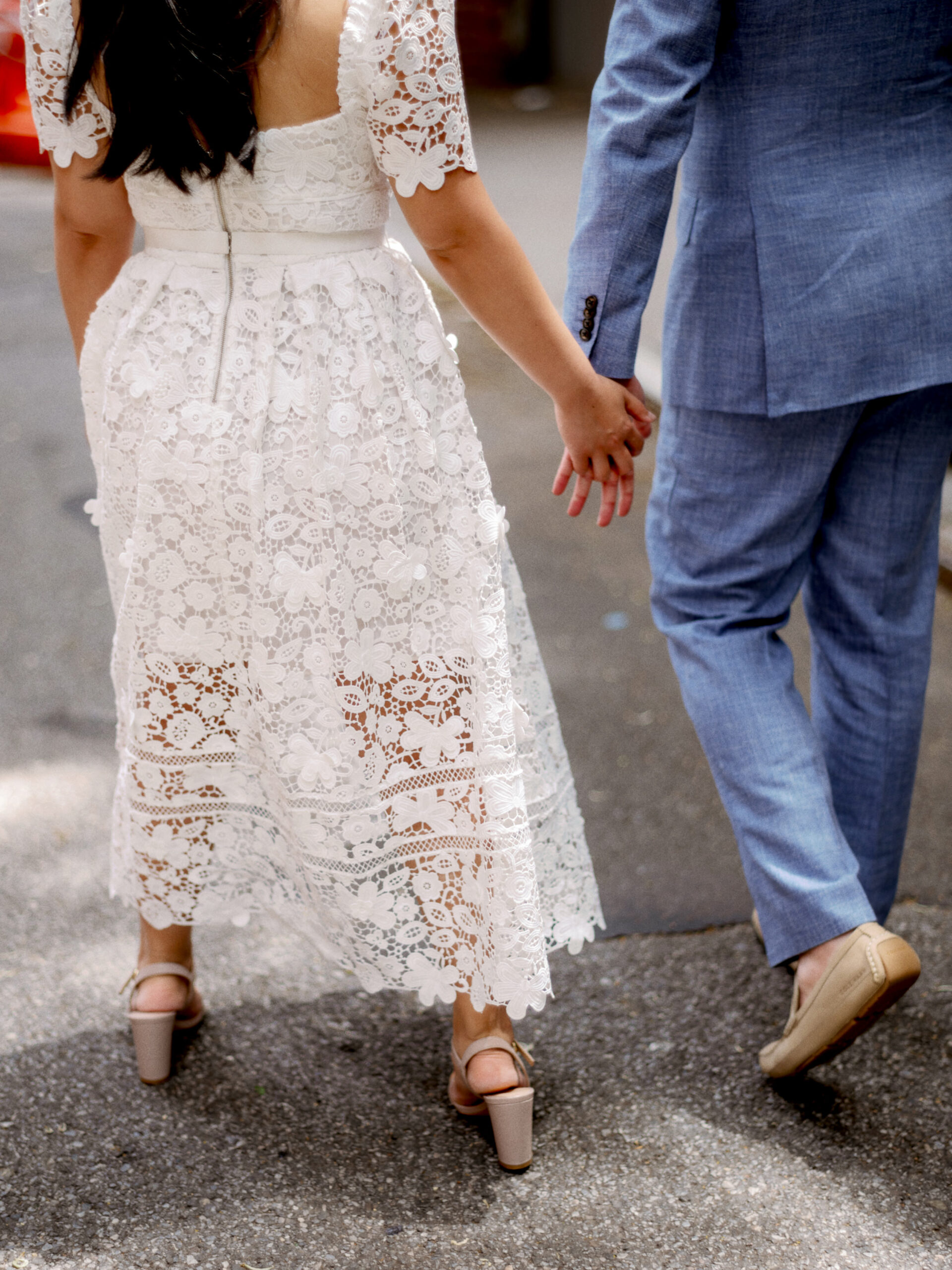 Lower half-body image of the engaged couple walking while holding hands. Image by Jenny Fu Studio