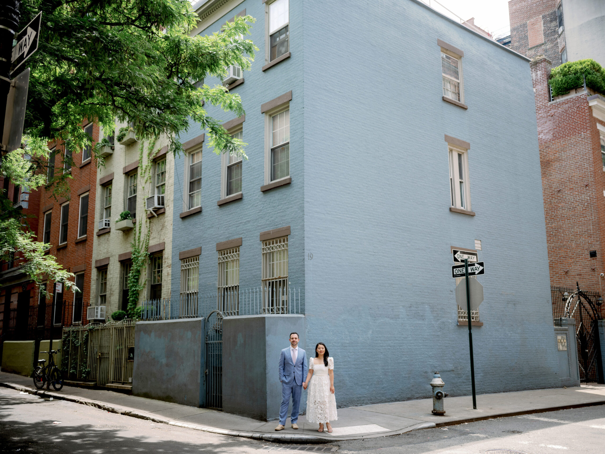 The engaged couple are standing with a blue building in the background. Engagement photos image by Jenny Fu Studio