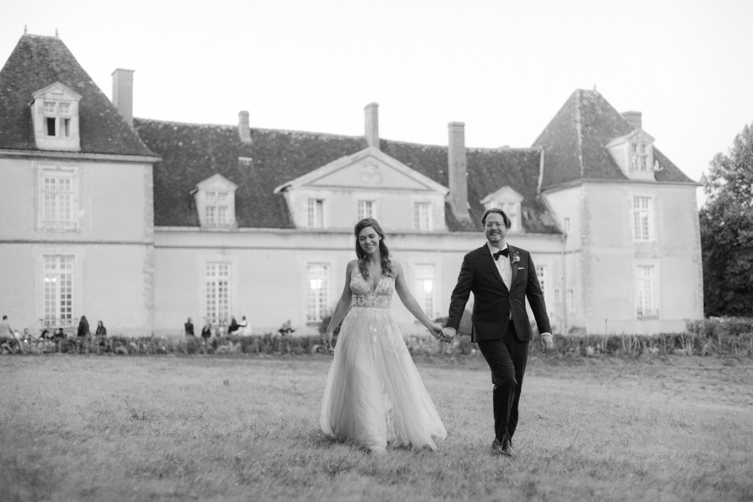 Black and white photo of the bride and groom in front of Chateau Du Fey. Image by Jenny Fu Studio