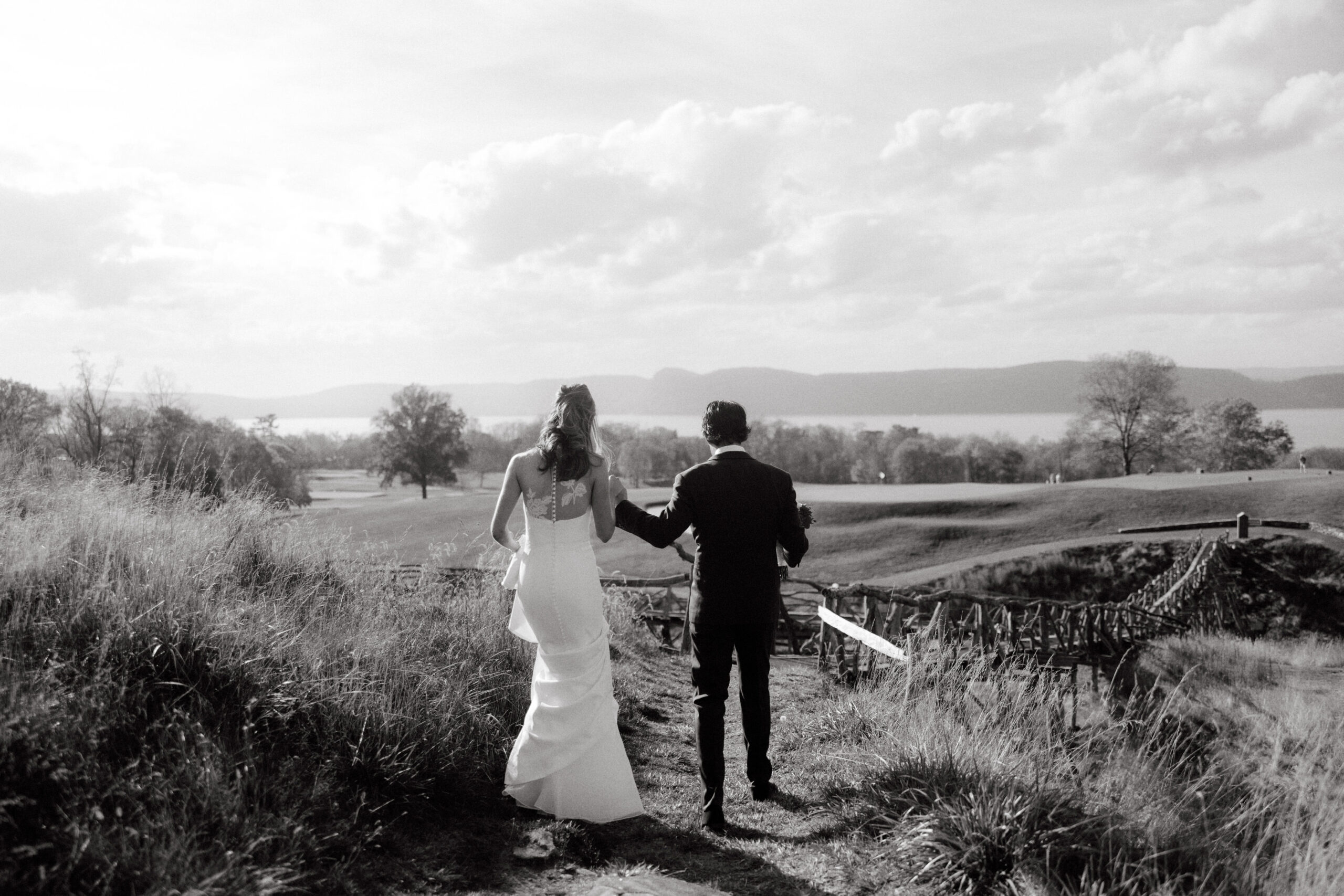 Black and white image of the bride and groom walking outdoors at Sleepy Hollow Countryclub, NY. Latest wedding trends image by Jenny Fu Studio