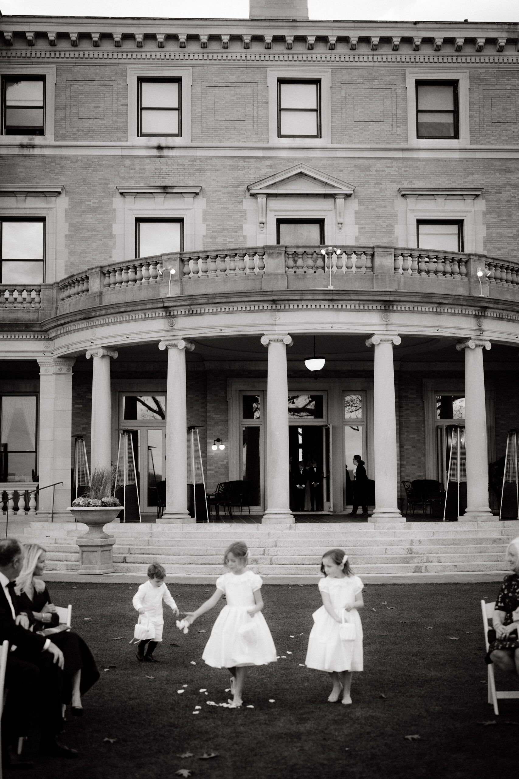 Black and white image of the flower girls walking in the aisle at Sleepy Hollow Country Club NY. Image by Jenny Fu Studio