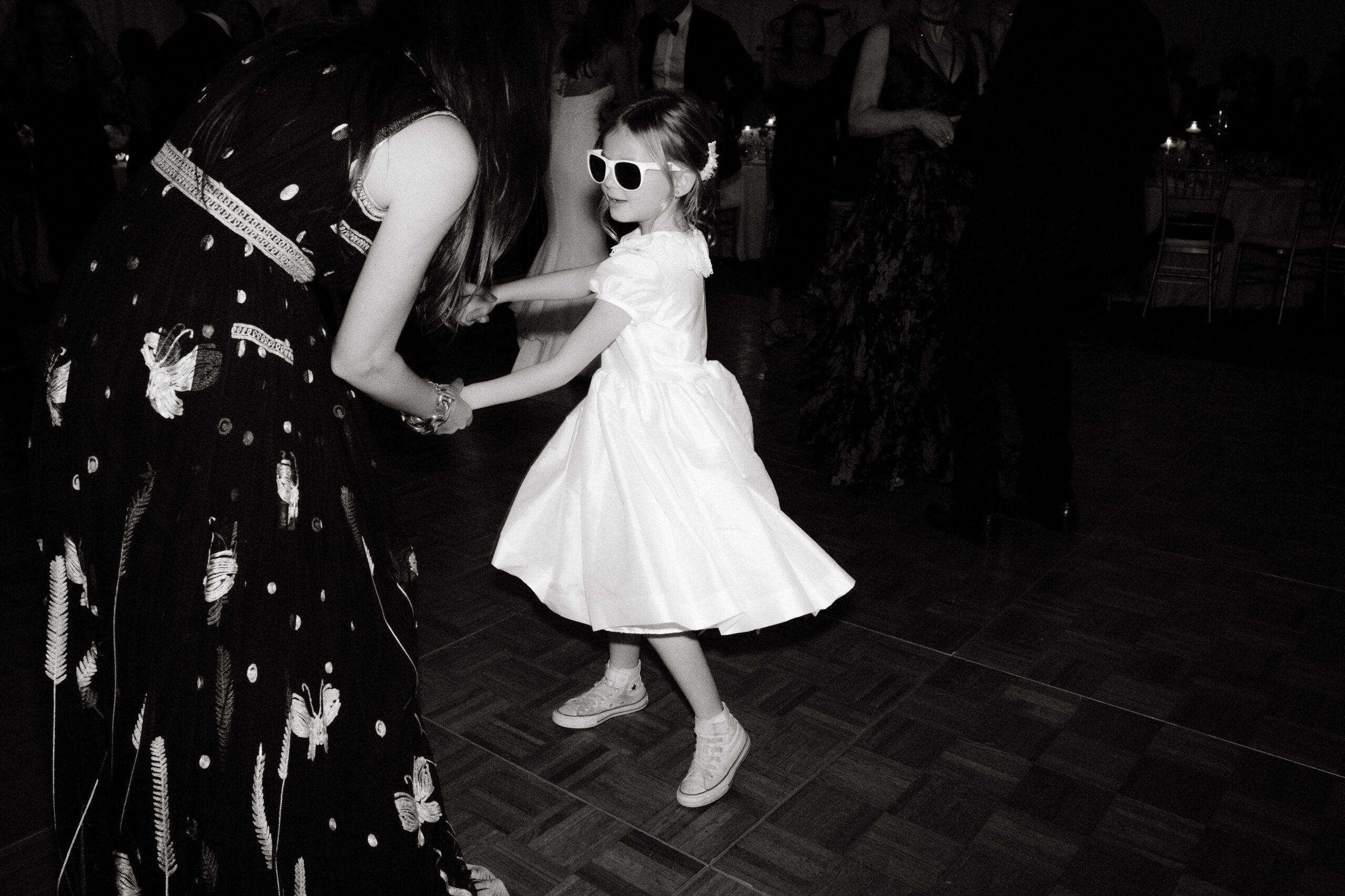 Black and white image of the flower girl wearing sunglasses while dancing on the dance floor. Image by Jenny Fu Studio