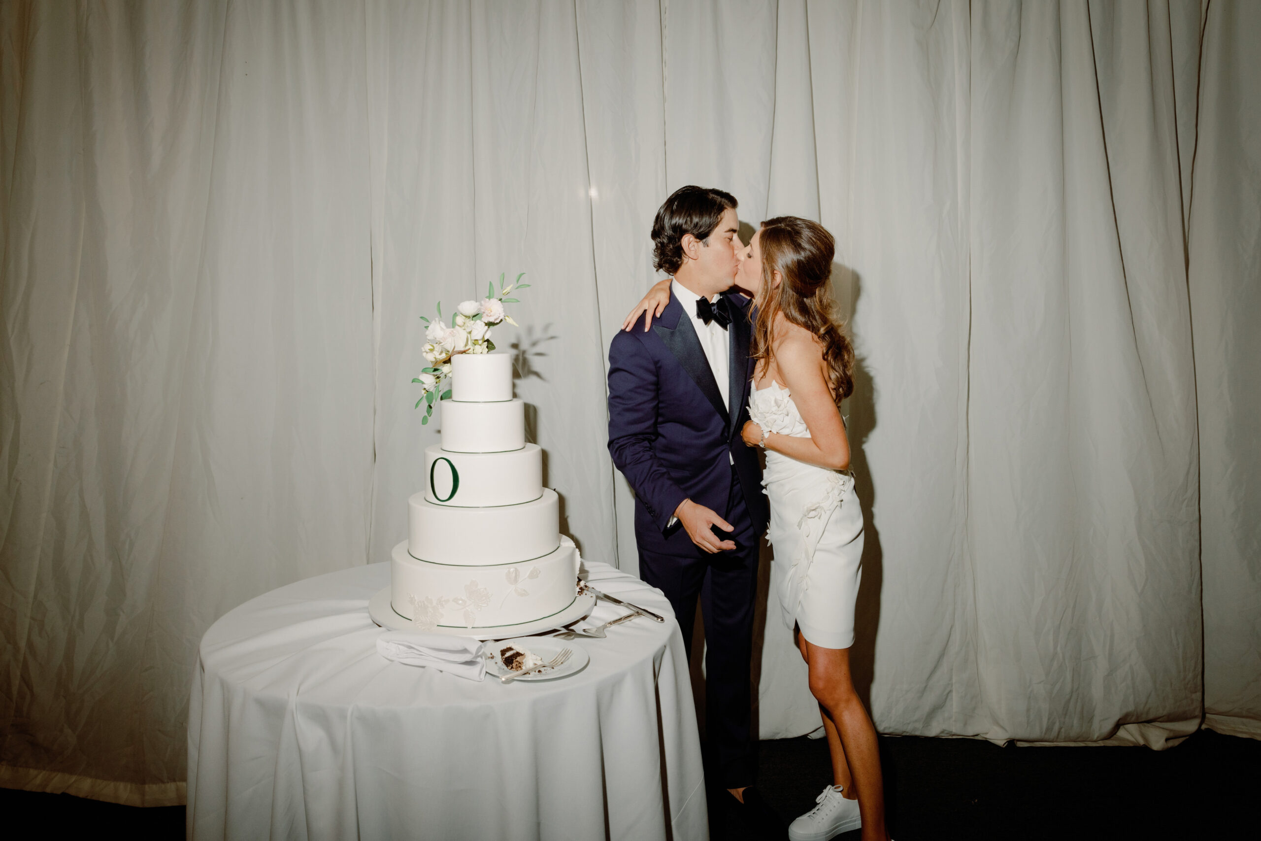 The bride and groom are kissing in the cake cutting ceremony. Image by Jenny Fu Studio