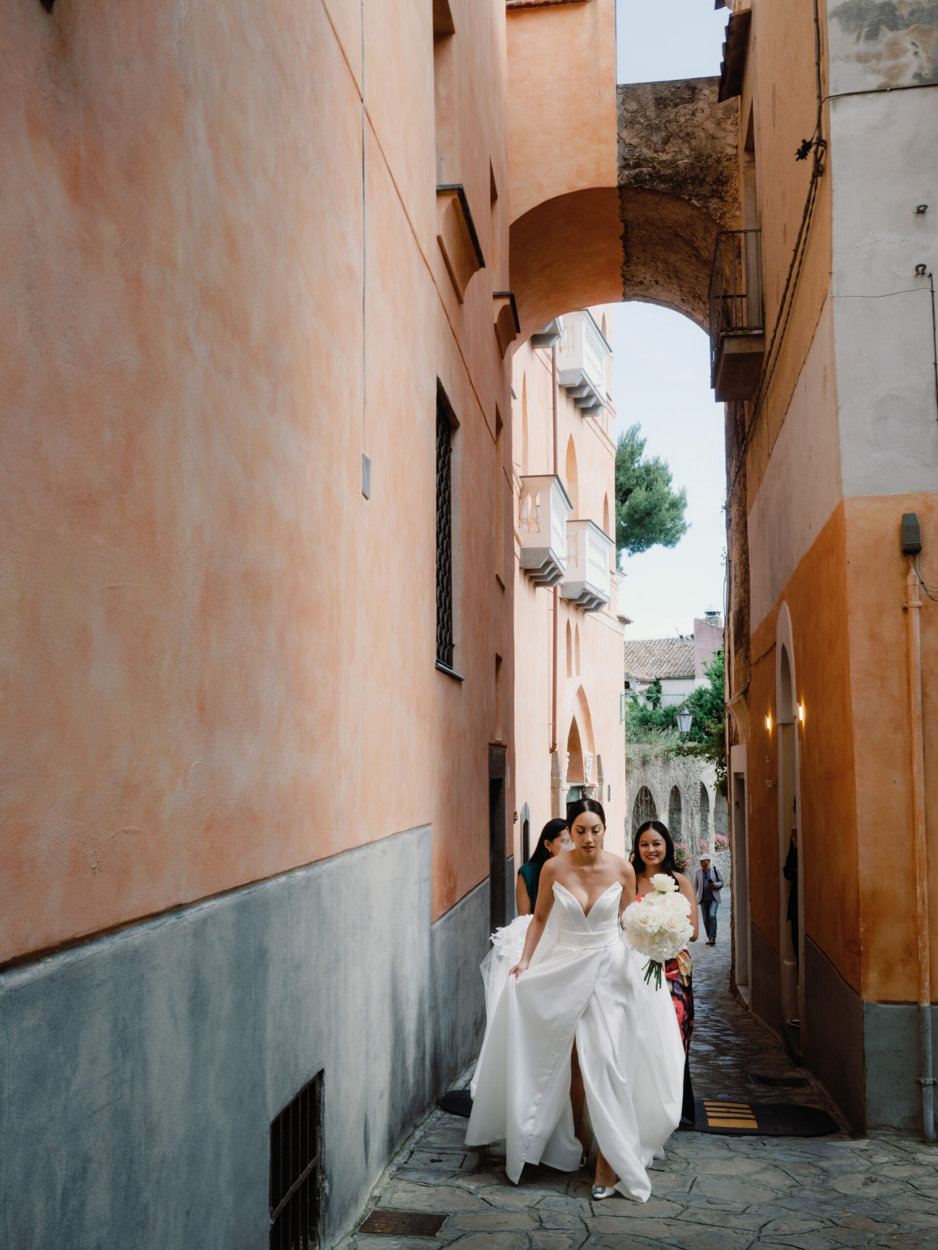 The bride is walking the narrow pathway in Italy. Editorial image by Jenny Fu Studio