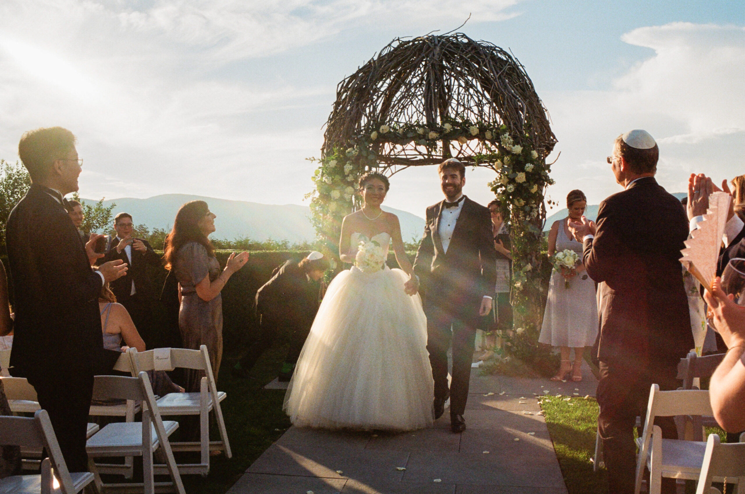 The couple is walking down the aisle after the wedding ceremony. Golden hour photo by Jenny Fu Studio