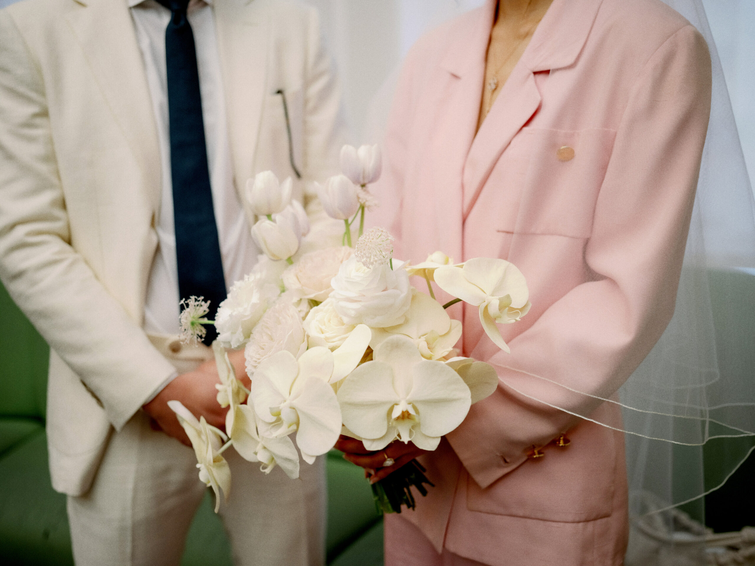 Bouquet of white flowers held by a bride at the Manhattan City Hall, NYC. Documentary Wedding Photography Image by Jenny Fu Studio