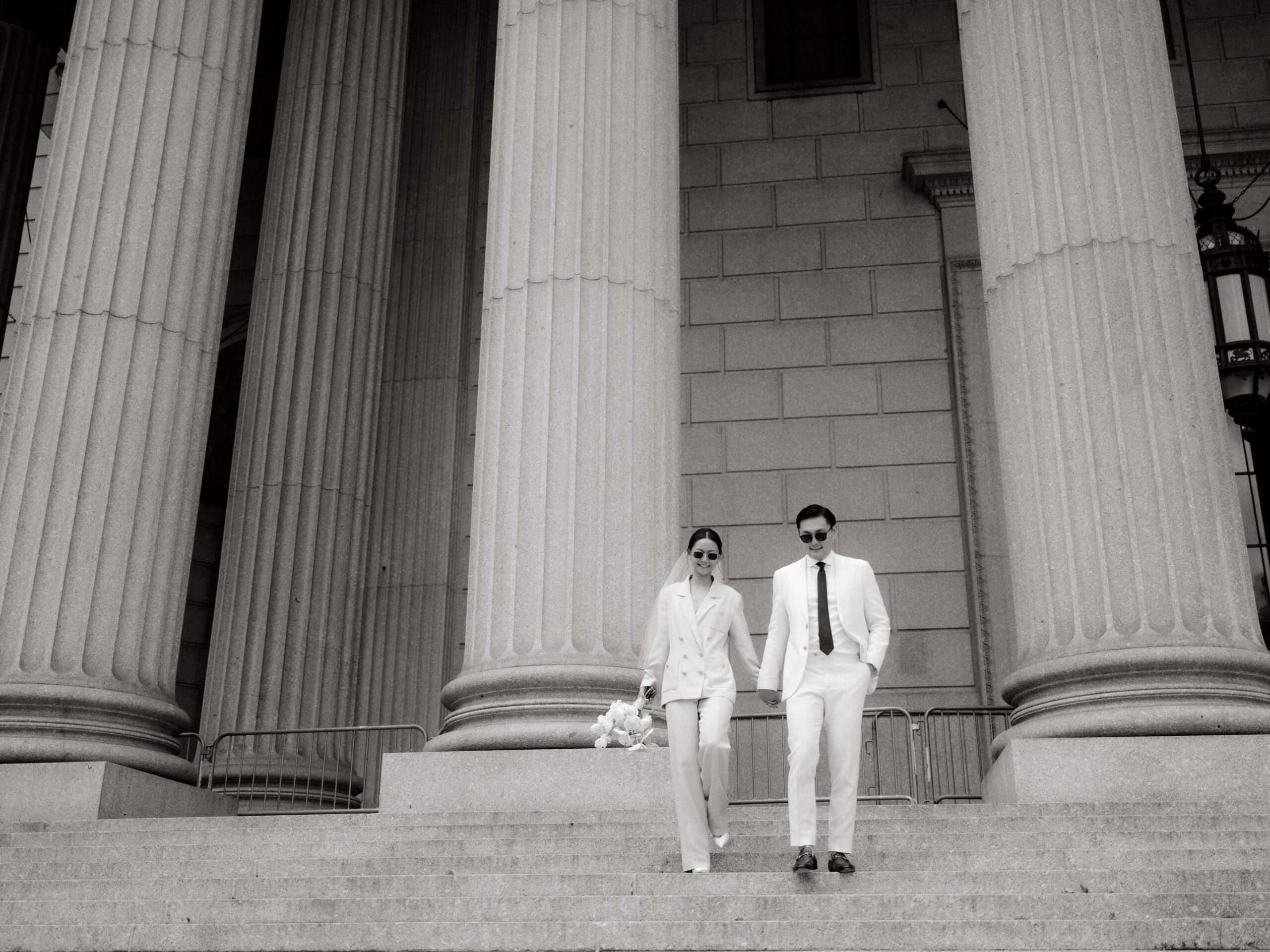 Editorial photo of the newlyweds going down the staircase of NY City Hall. Image by Jenny Fu Studio