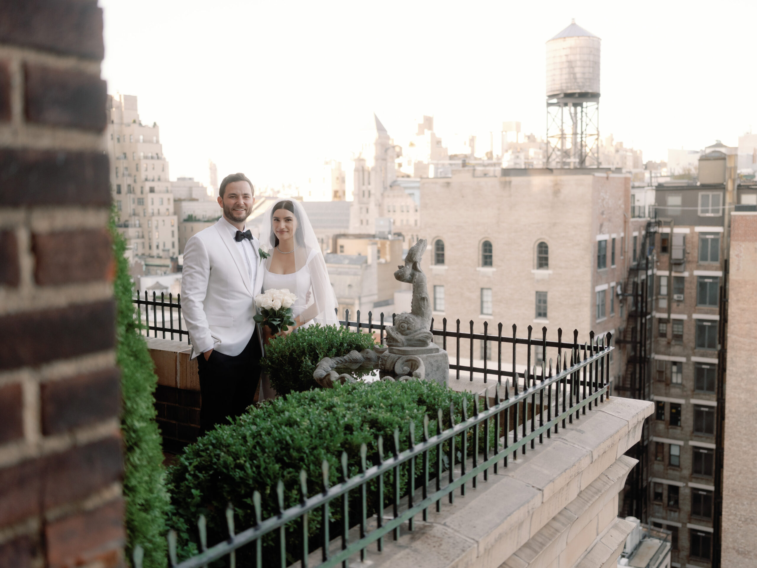 The newlyweds are standing in a veranda, with NYC buildings in the background. Image by Jenny Fu Studio