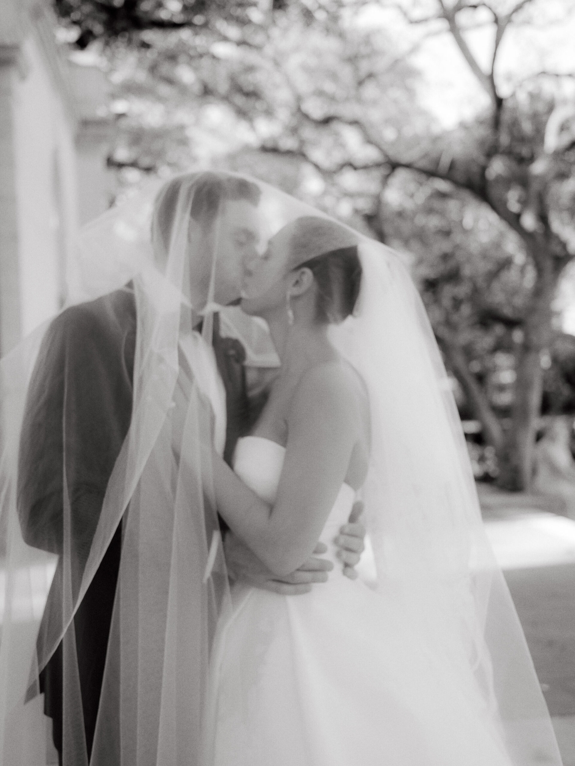 The newlyweds are kissing under the bride's veil. Image by Jenny Fu Studio