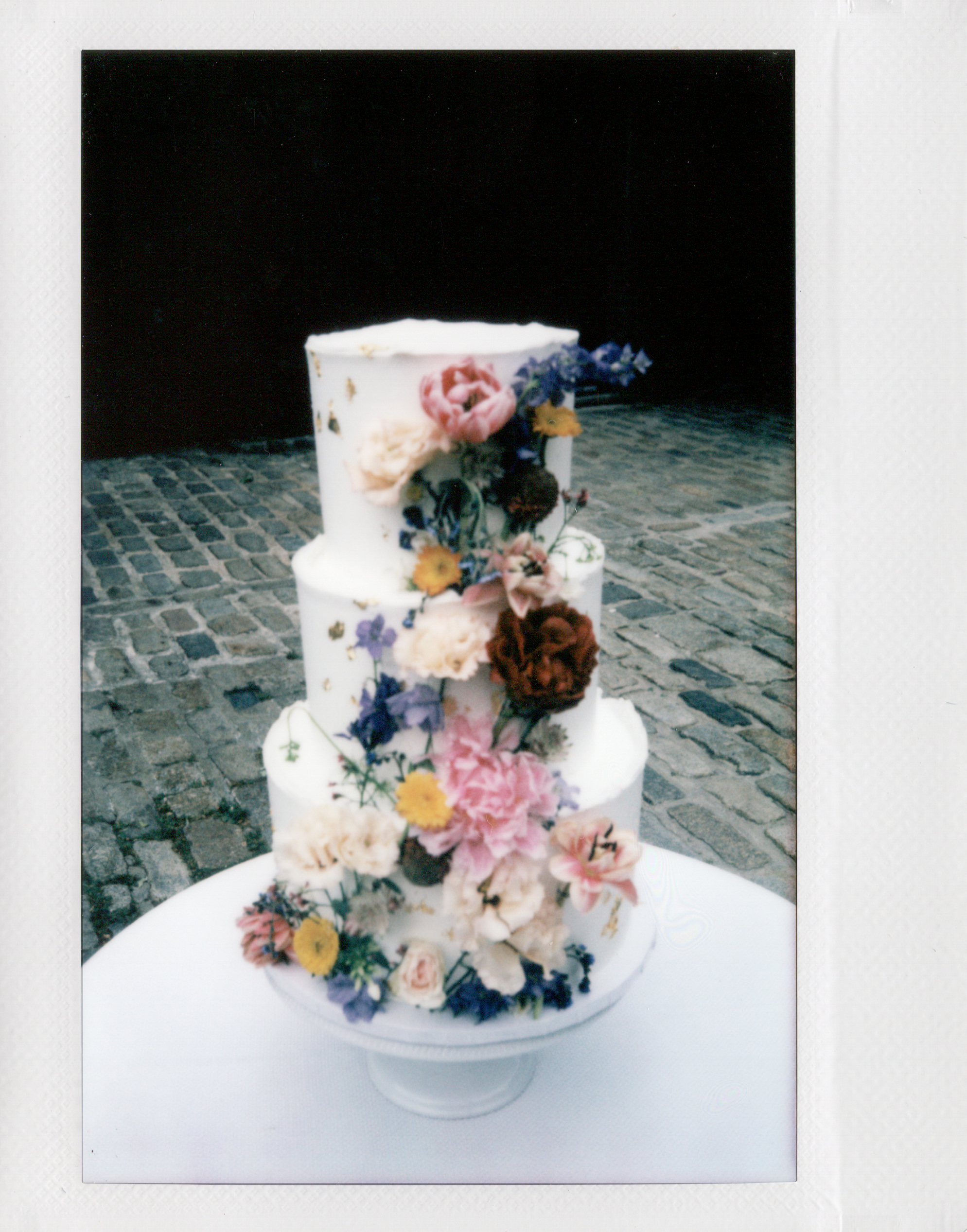 A beautiful wedding cake covered in flowers. Film photography image by Jenny Fu Studio