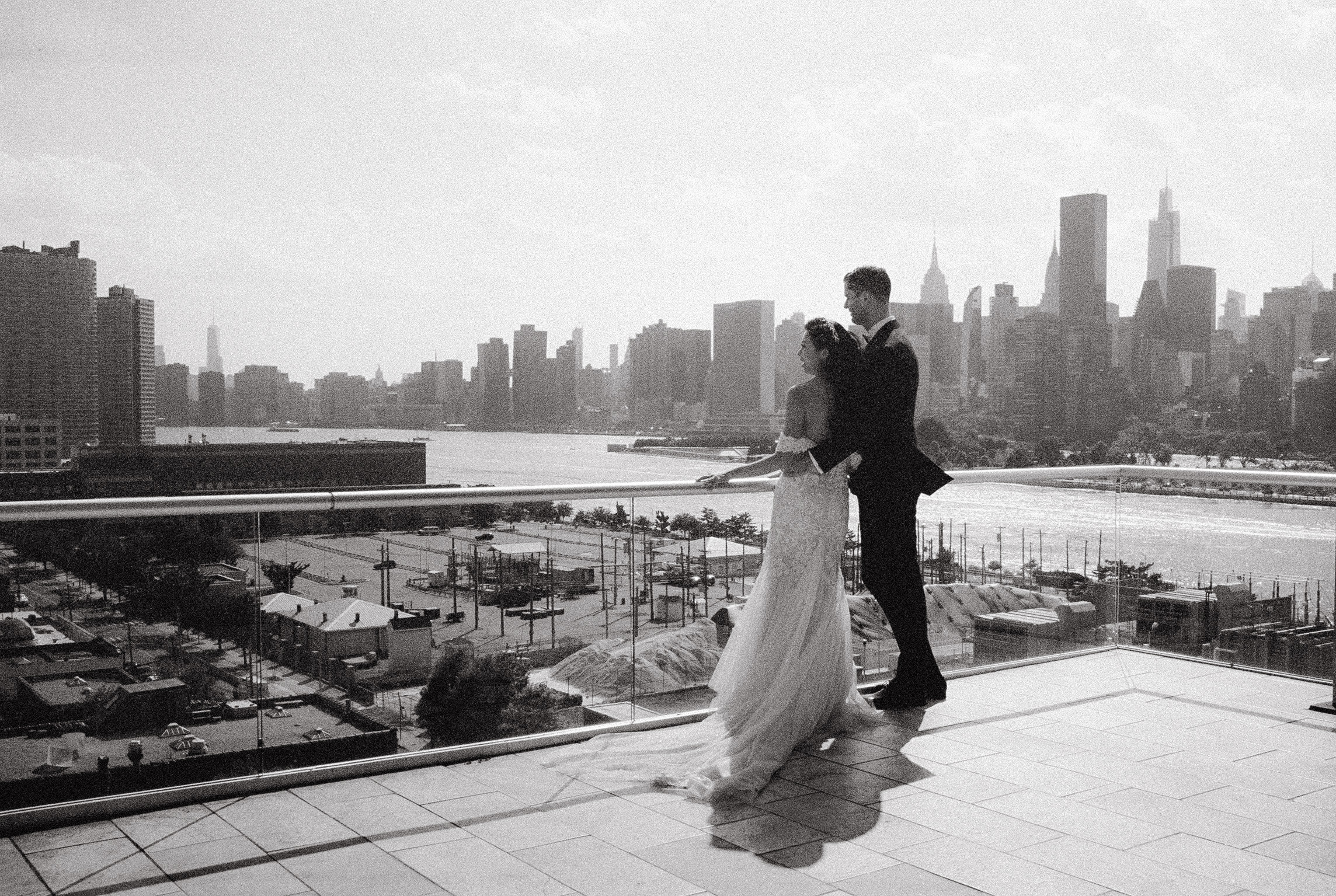 The bride and groom are looking towards the city, with NYC skyscrapers in the background. Image by Jenny Fu Studio