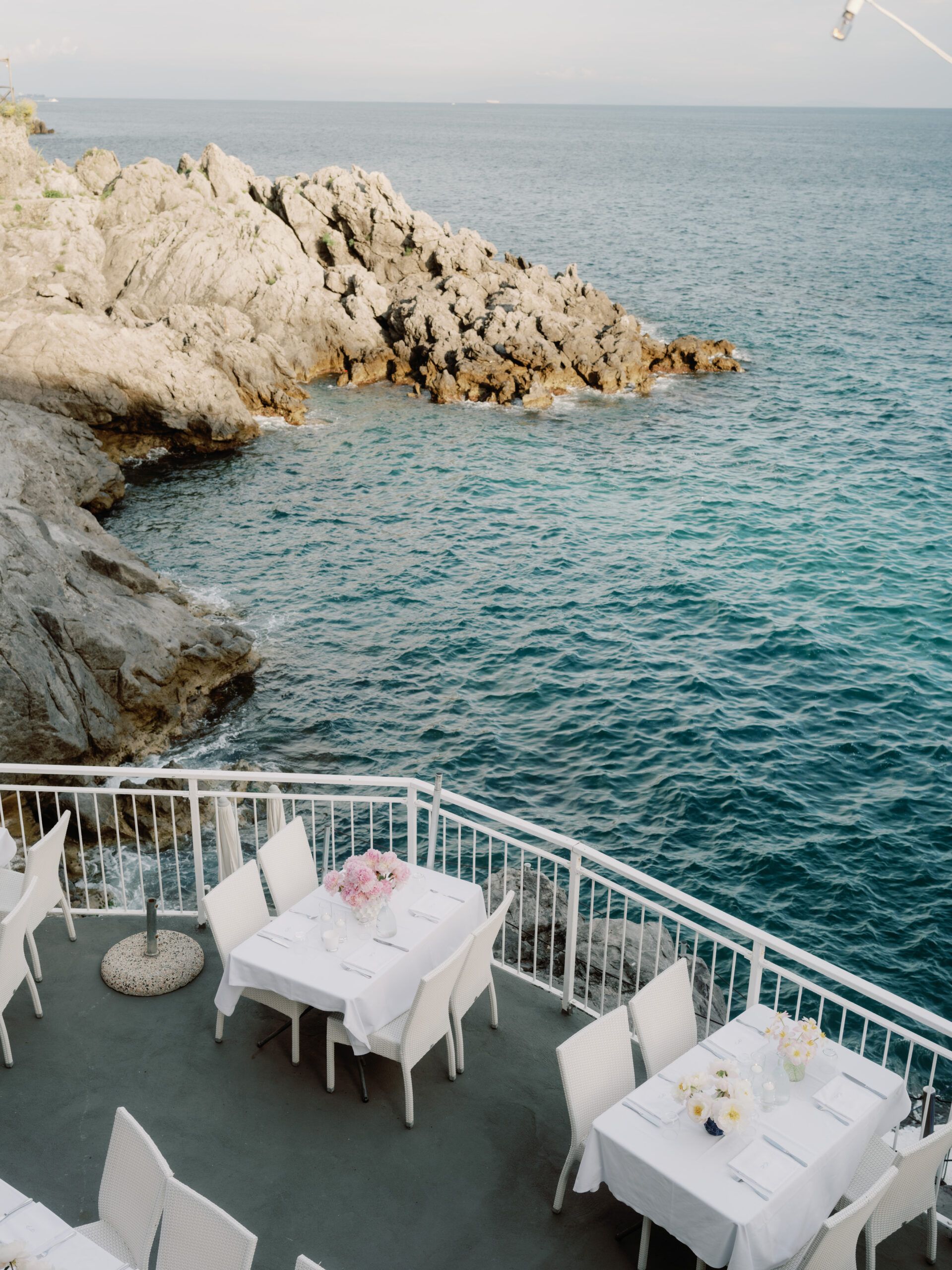 Editorial image of an outdoor table set-up on a terrace overlooking the sea. Image by Jenny Fu Studio