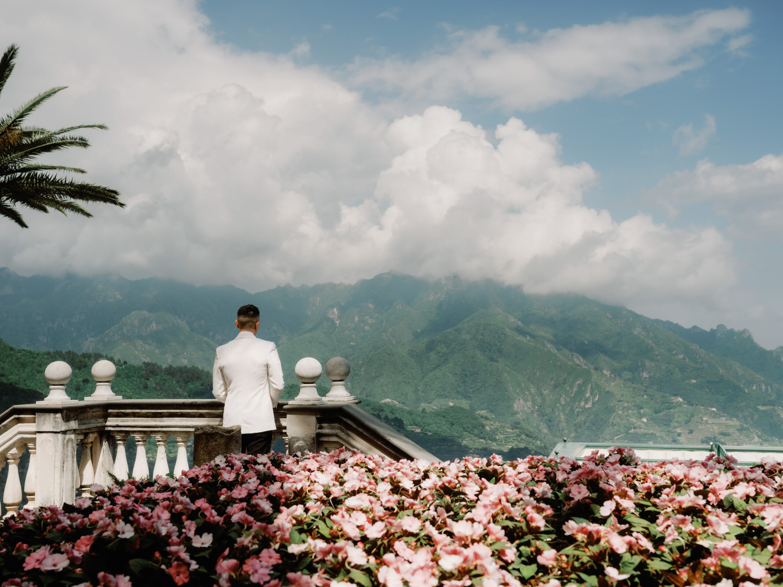 First look image of the groom overlooking mountain views for a wedding in Italy. Image by Jenny Fu Studio