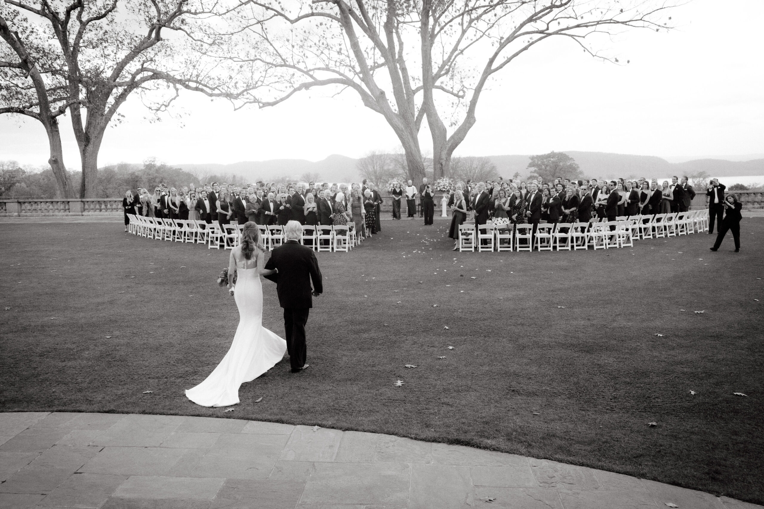 Editorial black and white photo of the bride walking down the aisle with her father. Image by Jenny Fu Studio