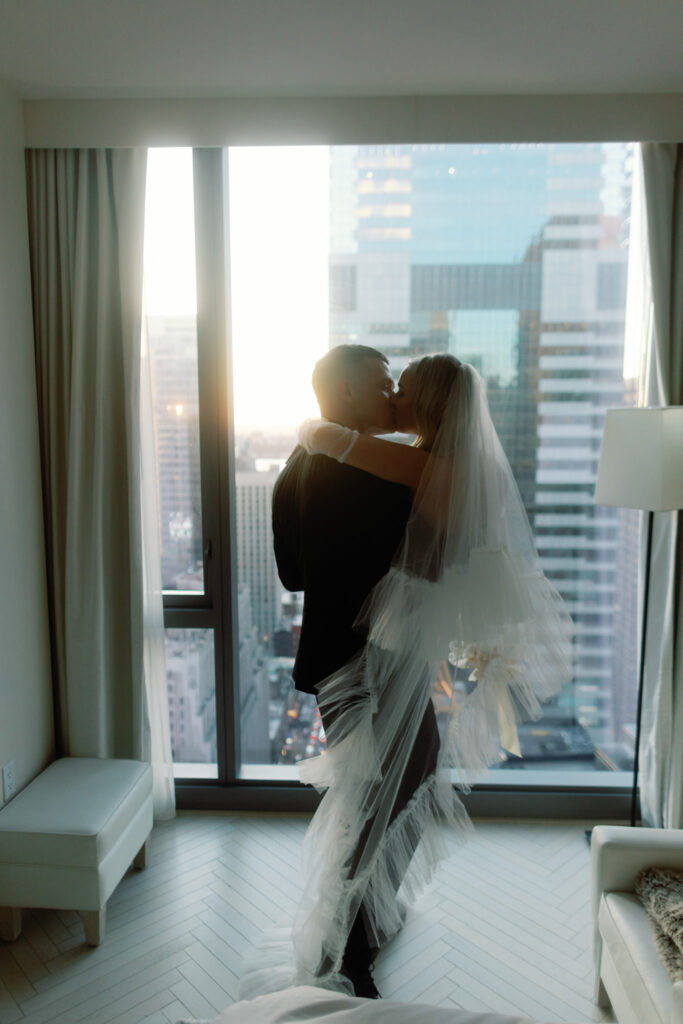 Captured in the intimate setting of a Times Square Manhattan hotel room, the bride and groom share a tender kiss that encapsulates the euphoria of their just-married bliss. The city's vibrant energy echoes outside the window as the couple, bathed in the warm glow of their love, celebrates the beginning of a new chapter against the iconic backdrop of Times Square.

In this cherished moment, the room becomes a sanctuary for their love, where the hustle and bustle of the city fade into the background. The kiss, a testament to their commitment, is framed by the allure of a city that never sleeps—a poetic beginning to their journey as a married couple.