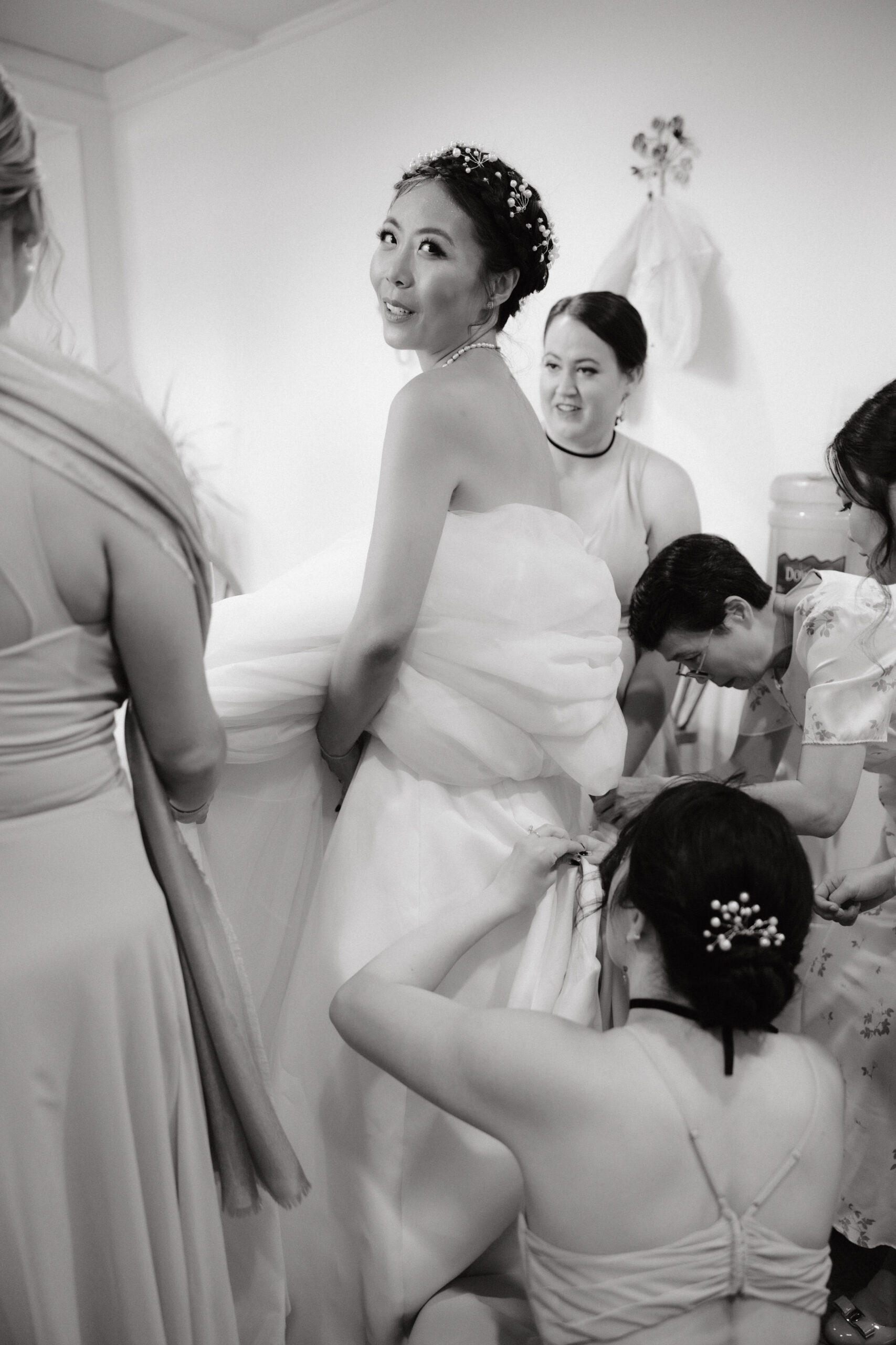 The mother of the bride and the bridesmaids are fixing the bride's wedding dress. Image by Jenny Fu Studio