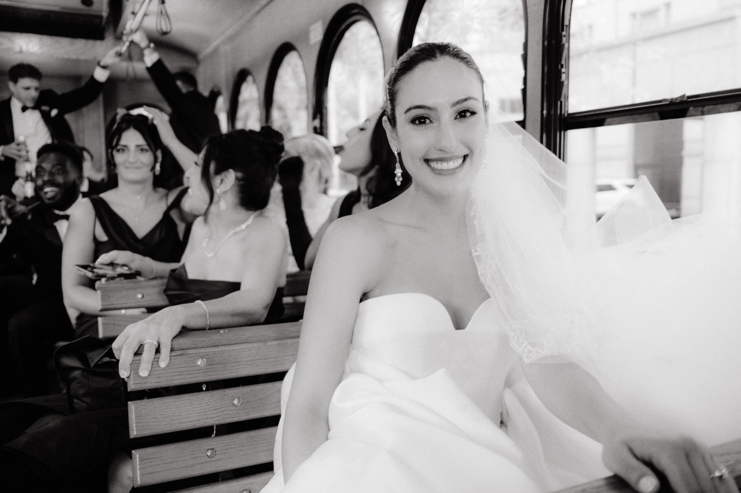 Black and white editorial photo of the bride and wedding entourage inside a bus. Image by Jenny Fu Studio