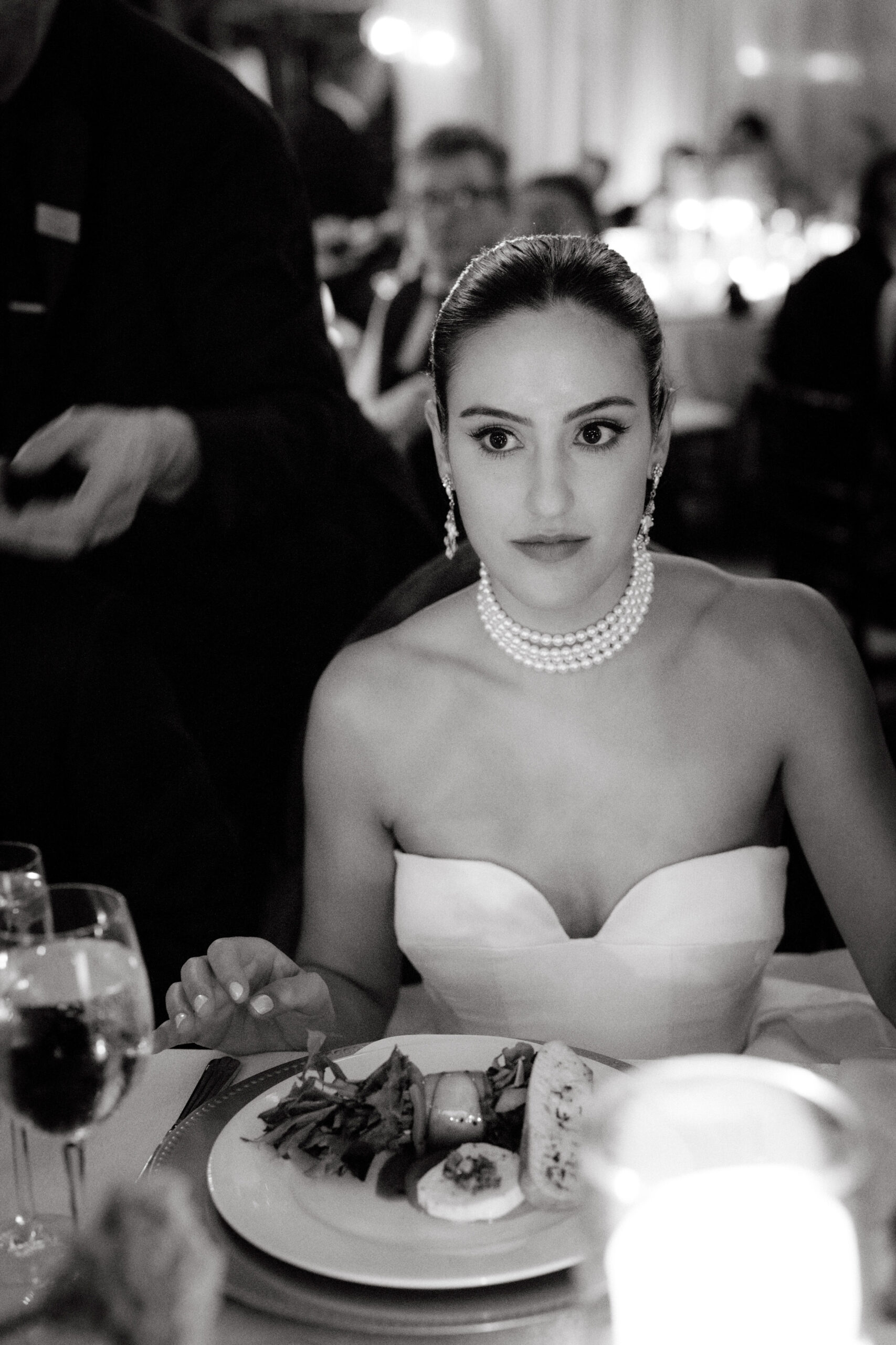 Black and white image of the beautiful bride sitting on the dinner table. Image by Jenny Fu Studio 