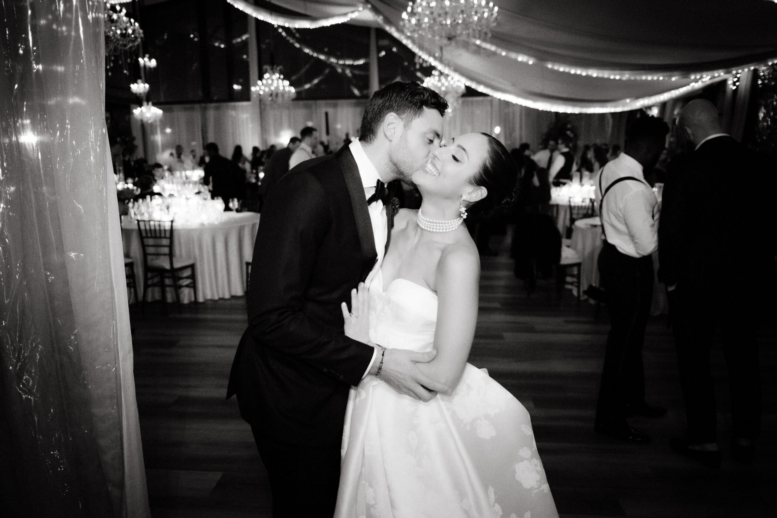 Candid black and white image of the groom kissing the bride on the dance floor. Image by Jenny Fu Studio
