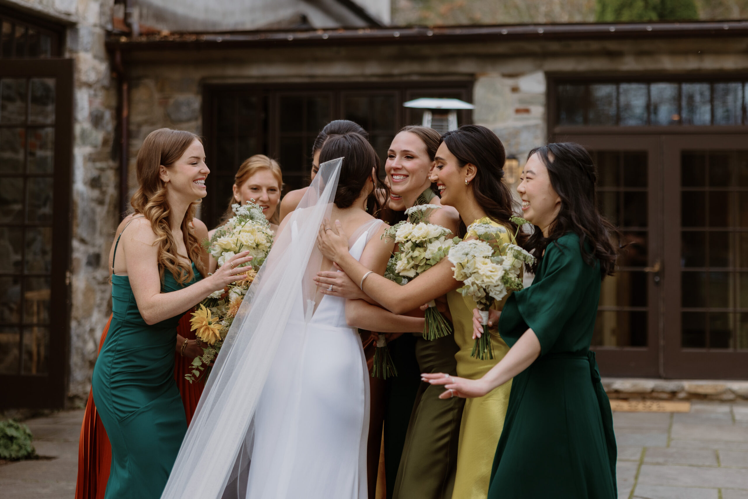 The bride and bridesmaids excitedly hugging each other before the first look. Photojournalistic wedding photography image by Jenny Fu Studio