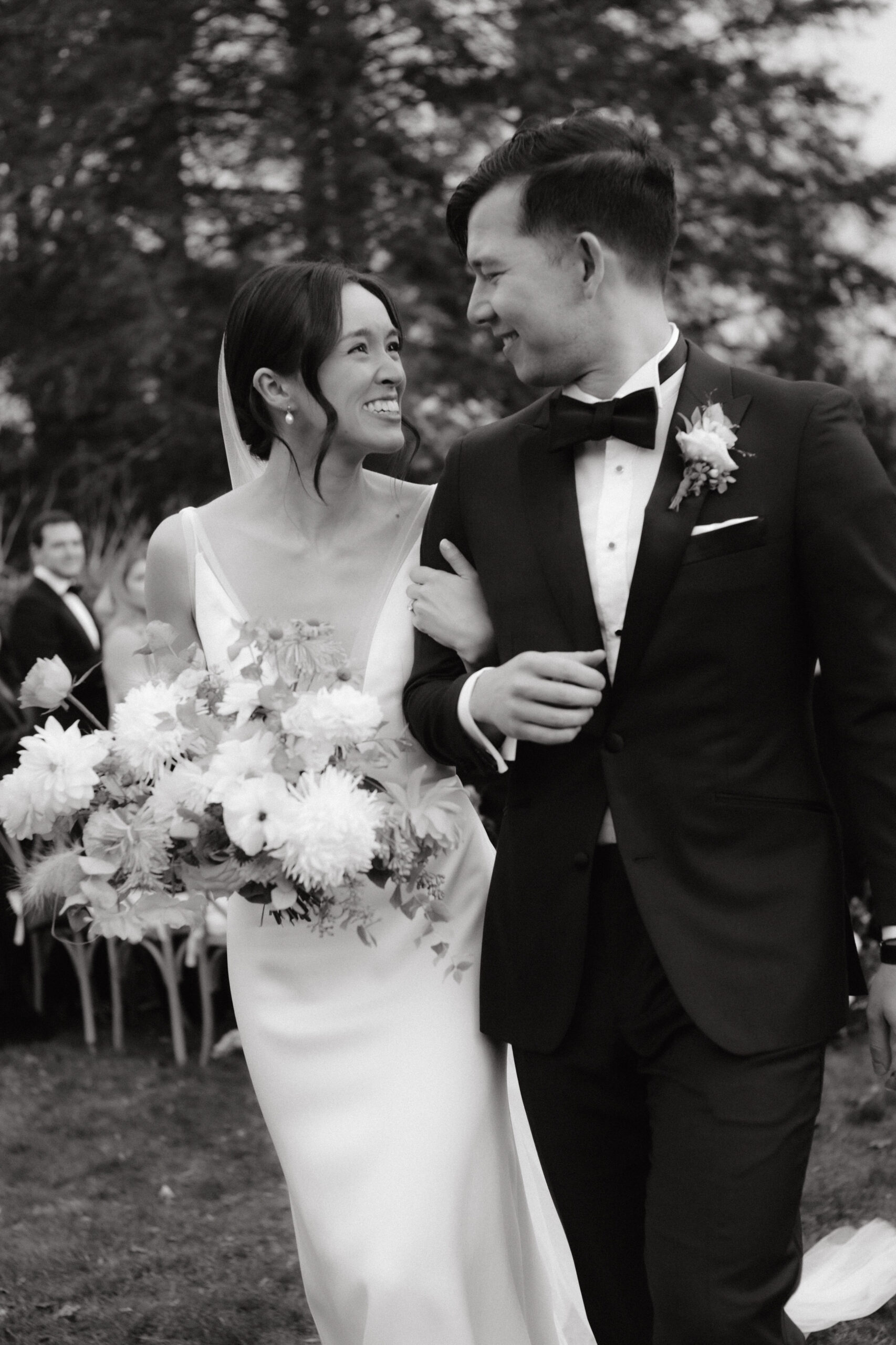 Black and white, candid image of the bride and groom walking down the aisle. Image by Jenny Fu Studio
