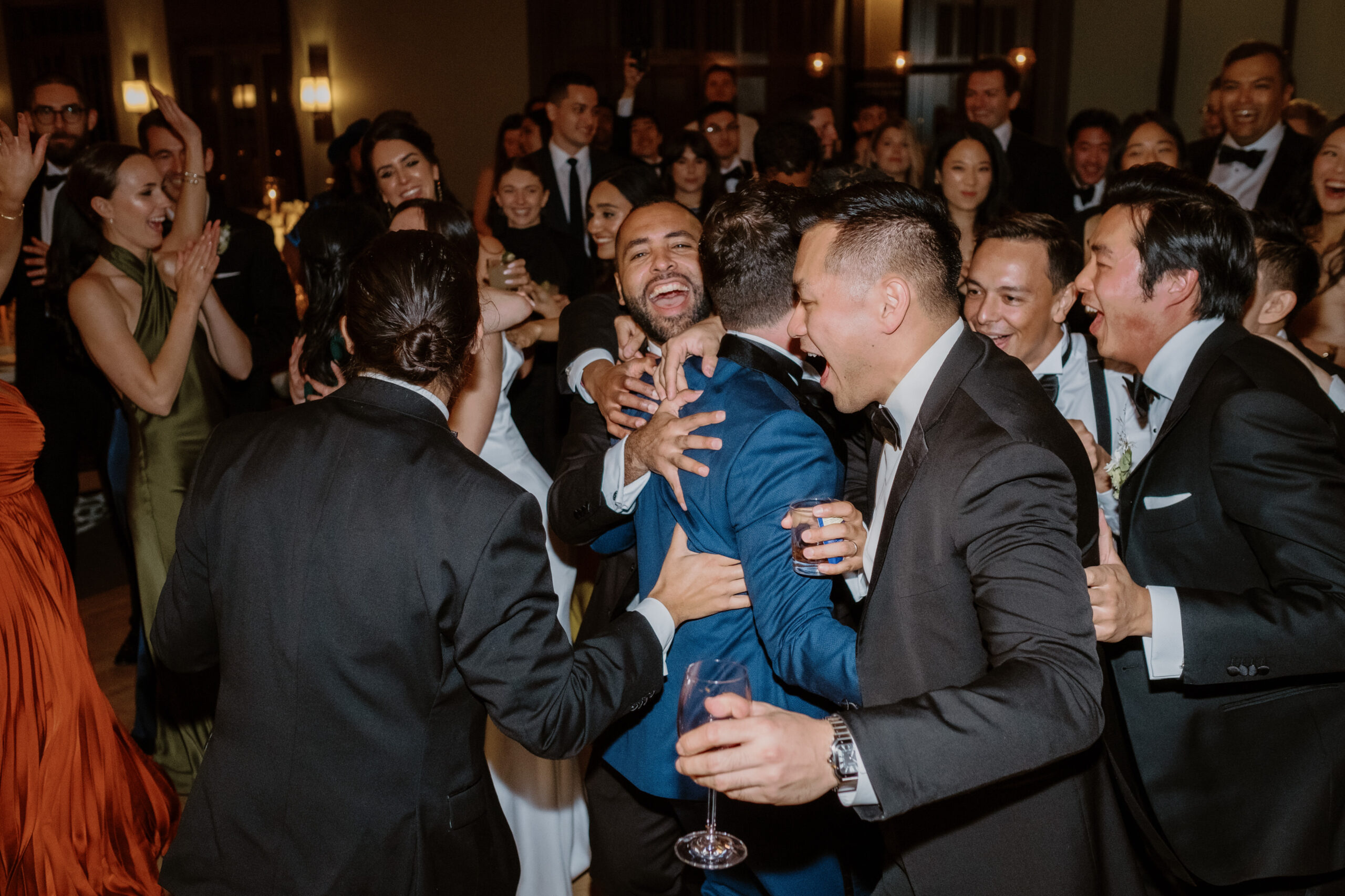The groomsmen are enthusiastically  hugging the groom on the dance floor. Image by Jenny Fu Studio