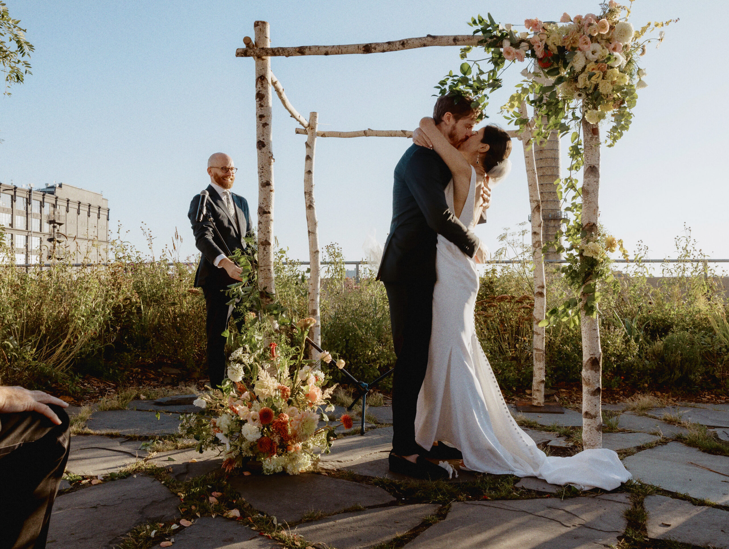 The bride and groom are kissing each other after the wedding ceremony at The Brooklyn Grange. Luxury wedding photography by Jenny Fu Studio
