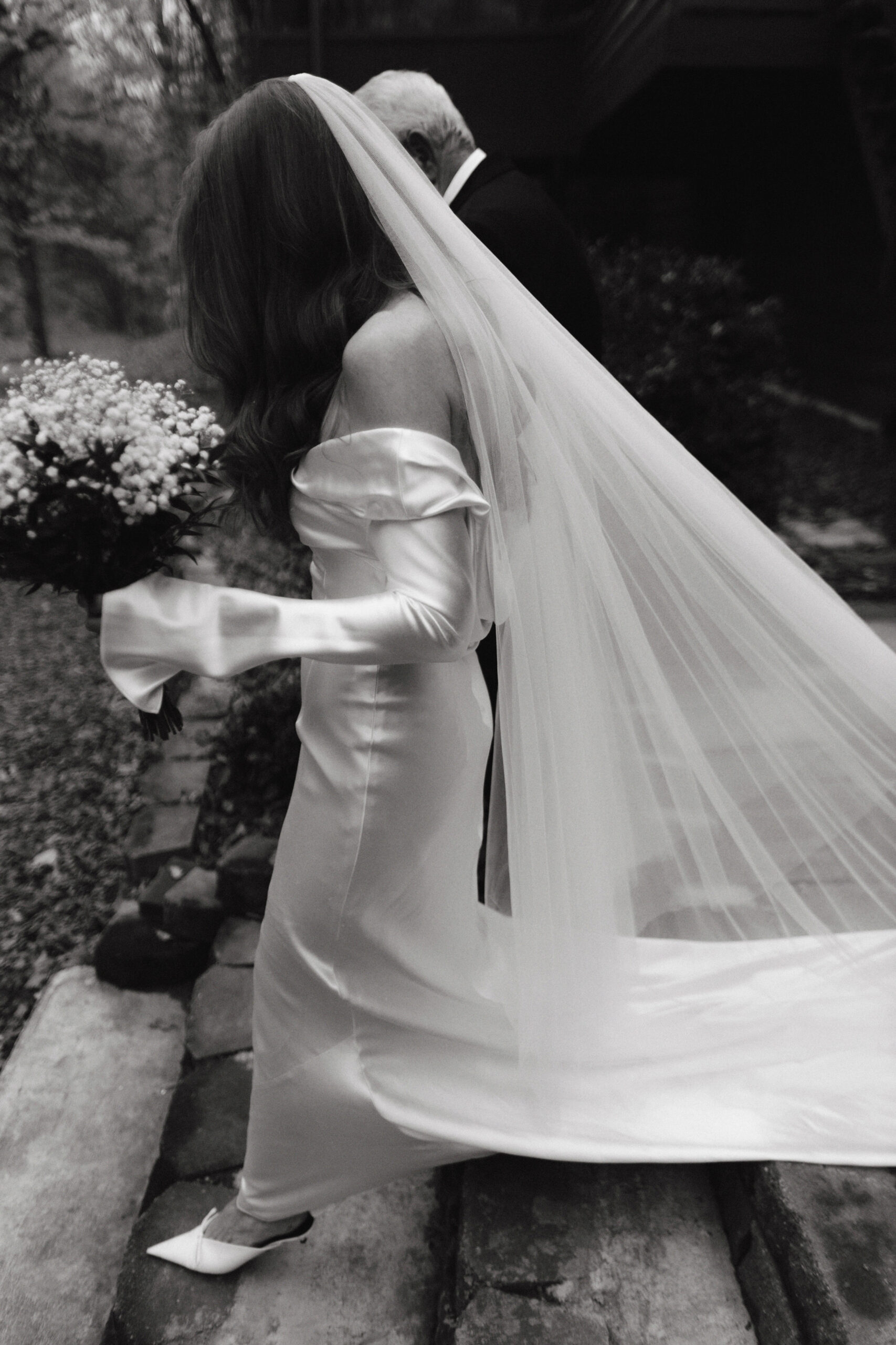 Black and white, documentary wedding photography photo of the bride going down the stairs. Image by Jenny Fu Studio