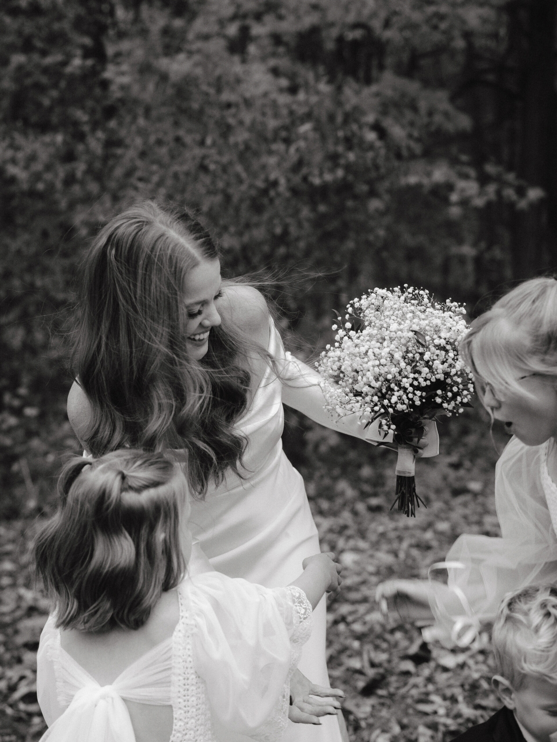 Black and white candid photo of the bride with her flower girls. Documentary wedding photography image by Jenny Fu Studio