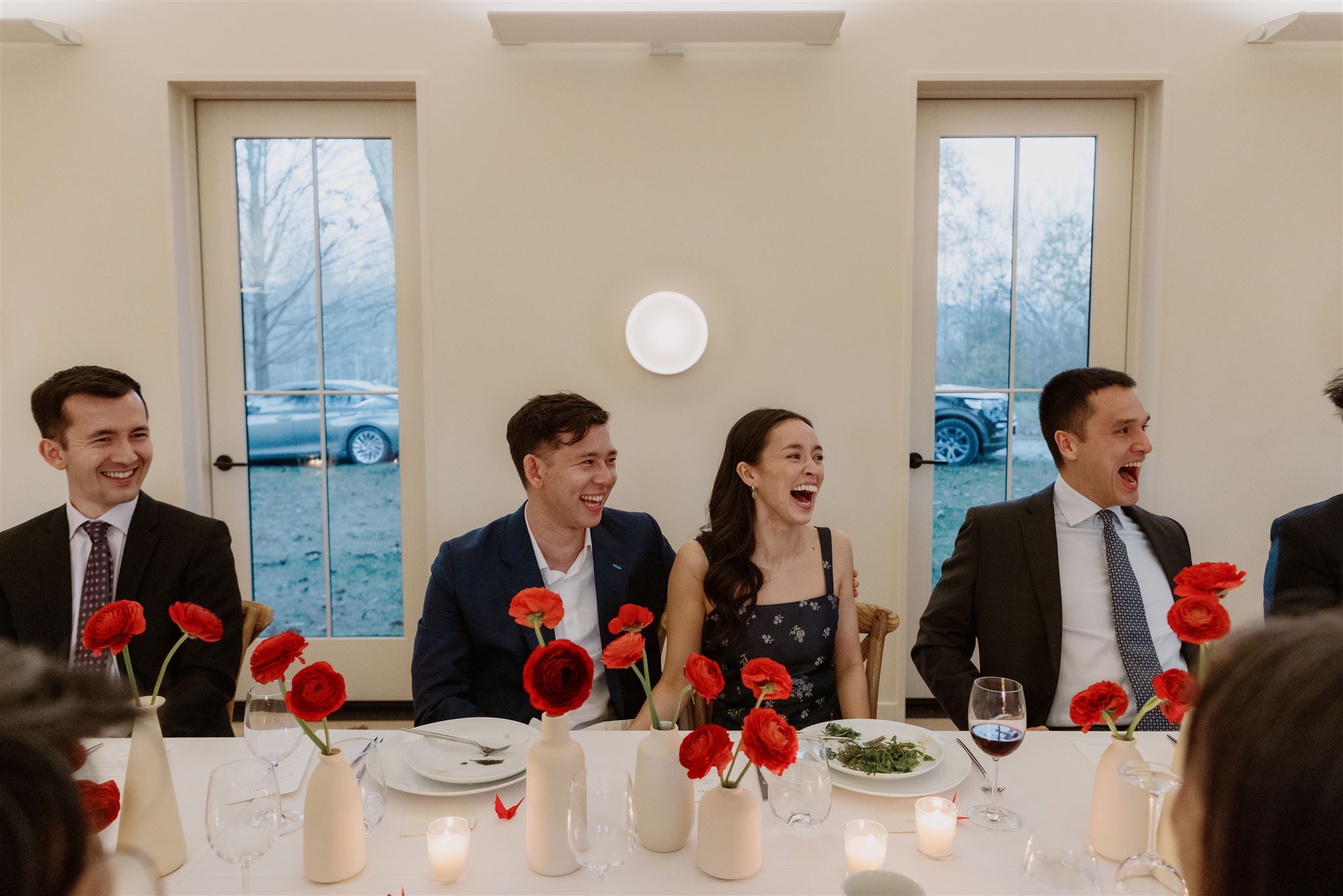 The bride and groom-to-be are heartily laughing with the guests at their welcome dinner. Documentary photography image by Jenny Fu Studio