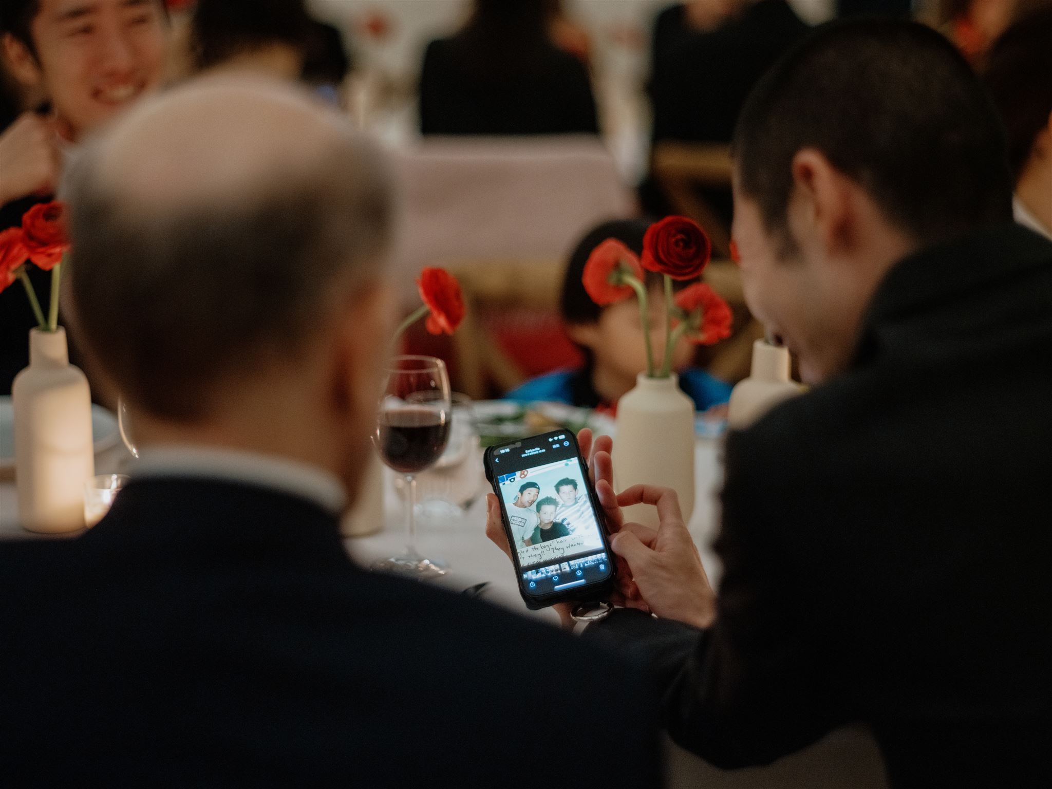 Candid photo of the guests chatting over a mobile phone at a welcome dinner in New York. Image by Jenny Fu Studio