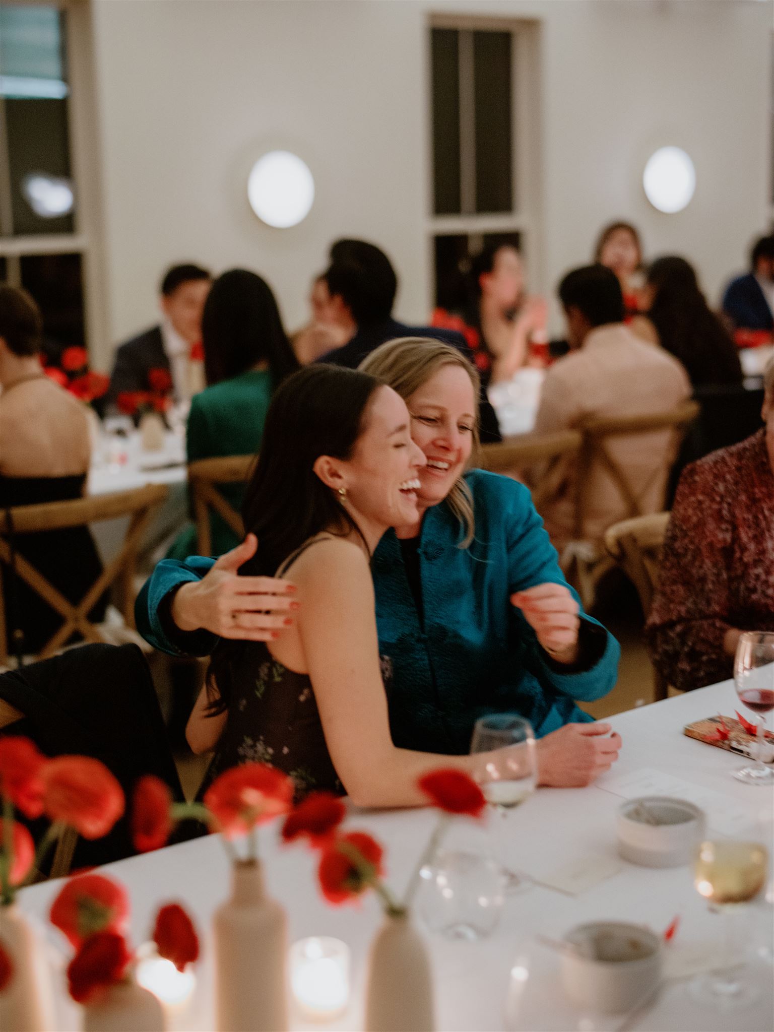The bride-to-be is happily hugging a guest at their welcome dinner in Troutbeck, New York. Candid image by Jenny Fu Studio