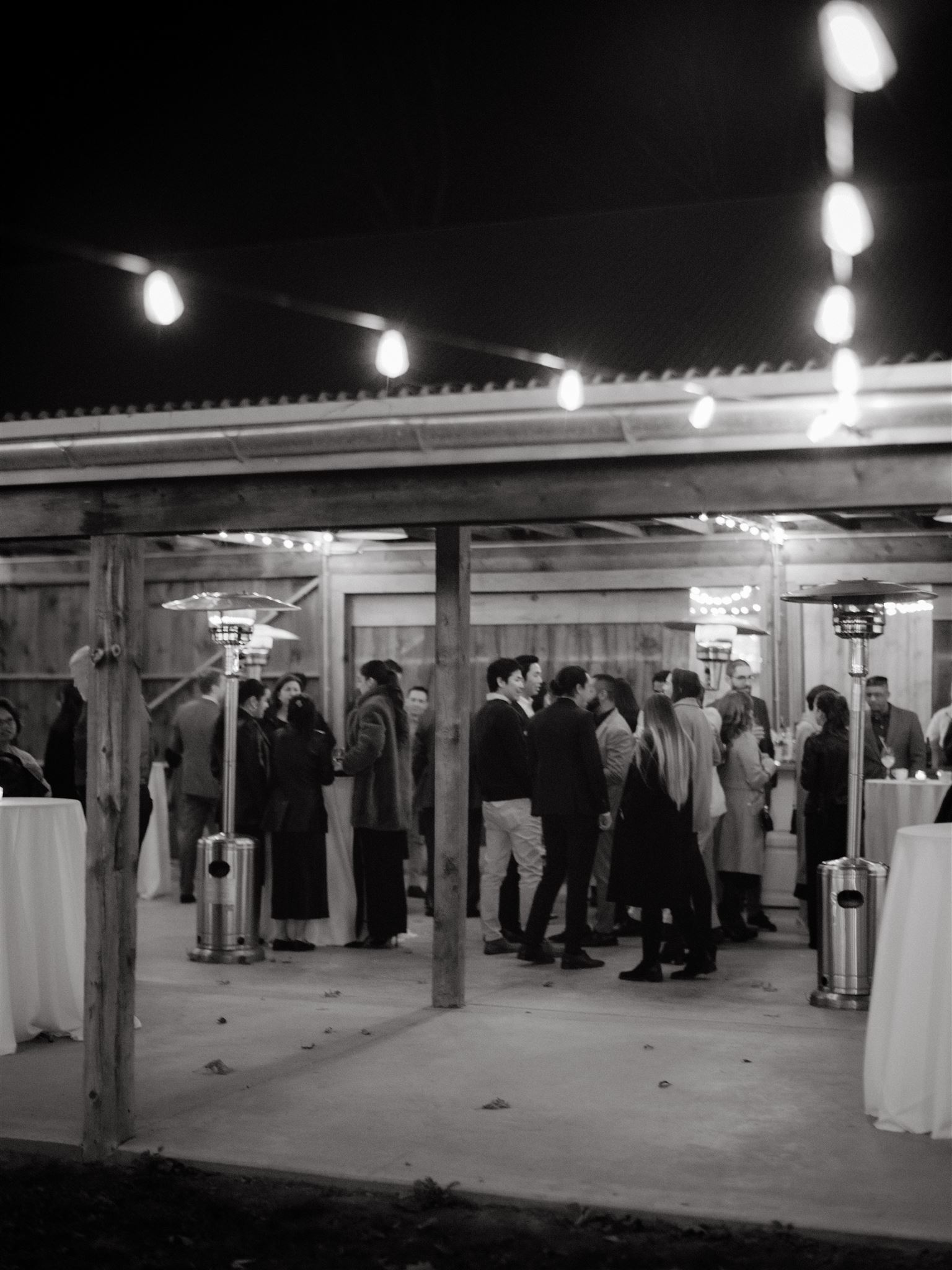 Black and white documentary image of the wedding dinner guests mingling with each other in New York. Image by Jenny Fu Studio