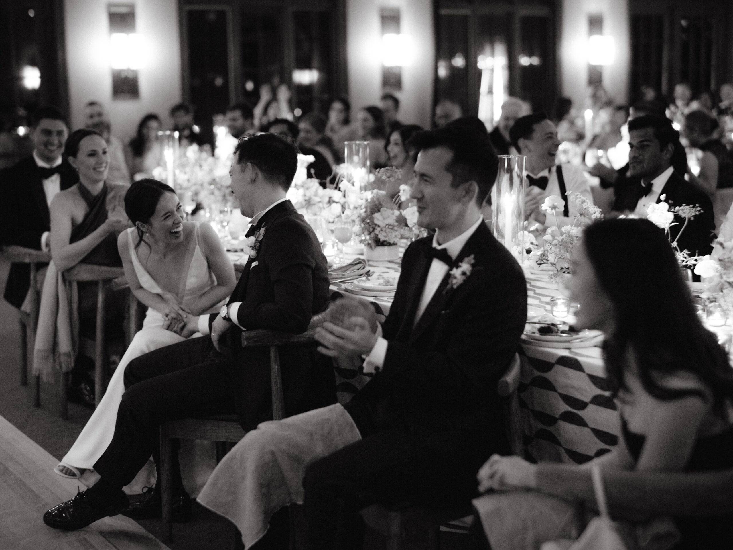 Black and white photo of the bride, groom, and guests having fun in the wedding reception. Photojournalistic wedding photography image by Jenny Fu Studio