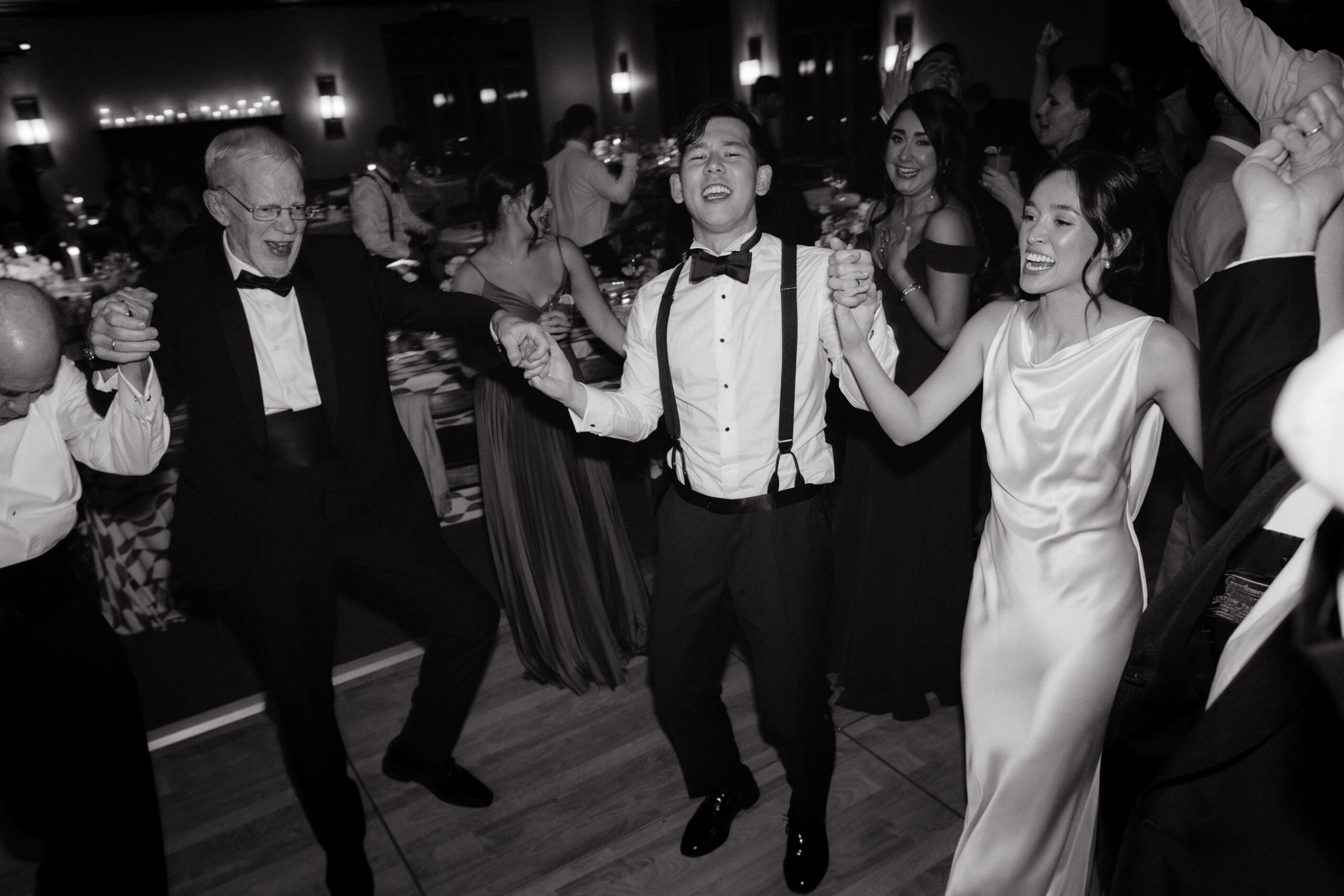 Candid photo of the bride, groom and guests dancing on the dance floor. Photojournalistic wedding photography image by Jenny Fu Studio