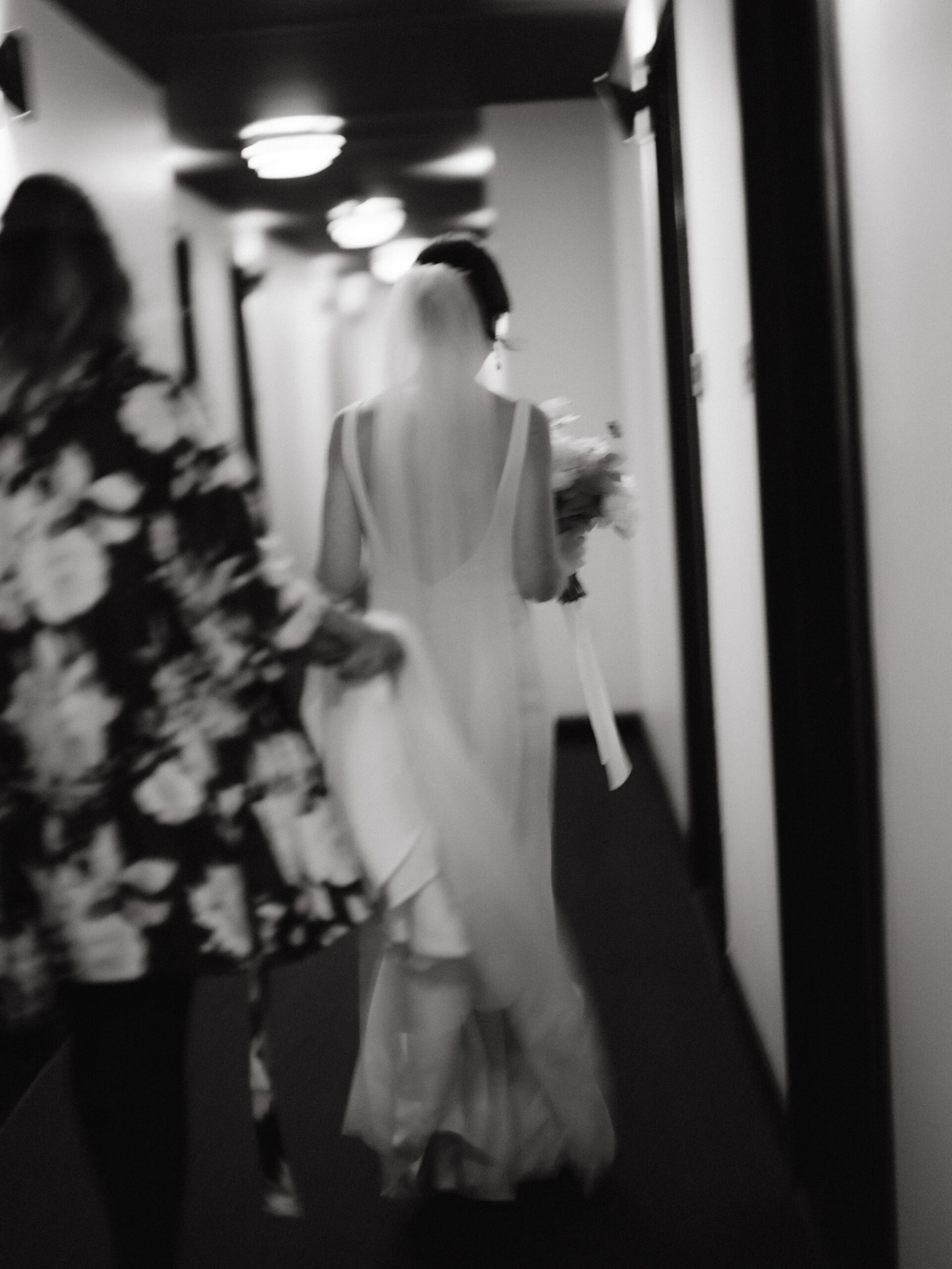 The bride is walking while a woman is holding her train. Photo by Jenny Fu Studio. 