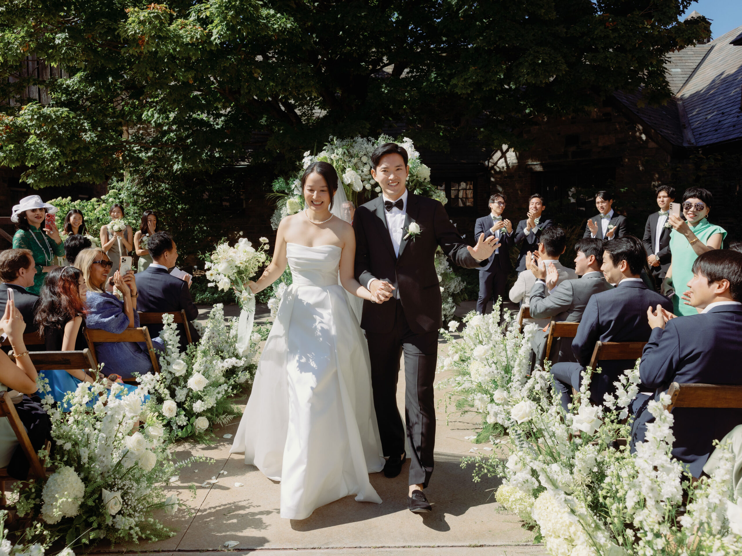 The newlyweds are happily walking back the aisle as the guests cheer on. Candid wedding photography image by Jenny Fu Studio